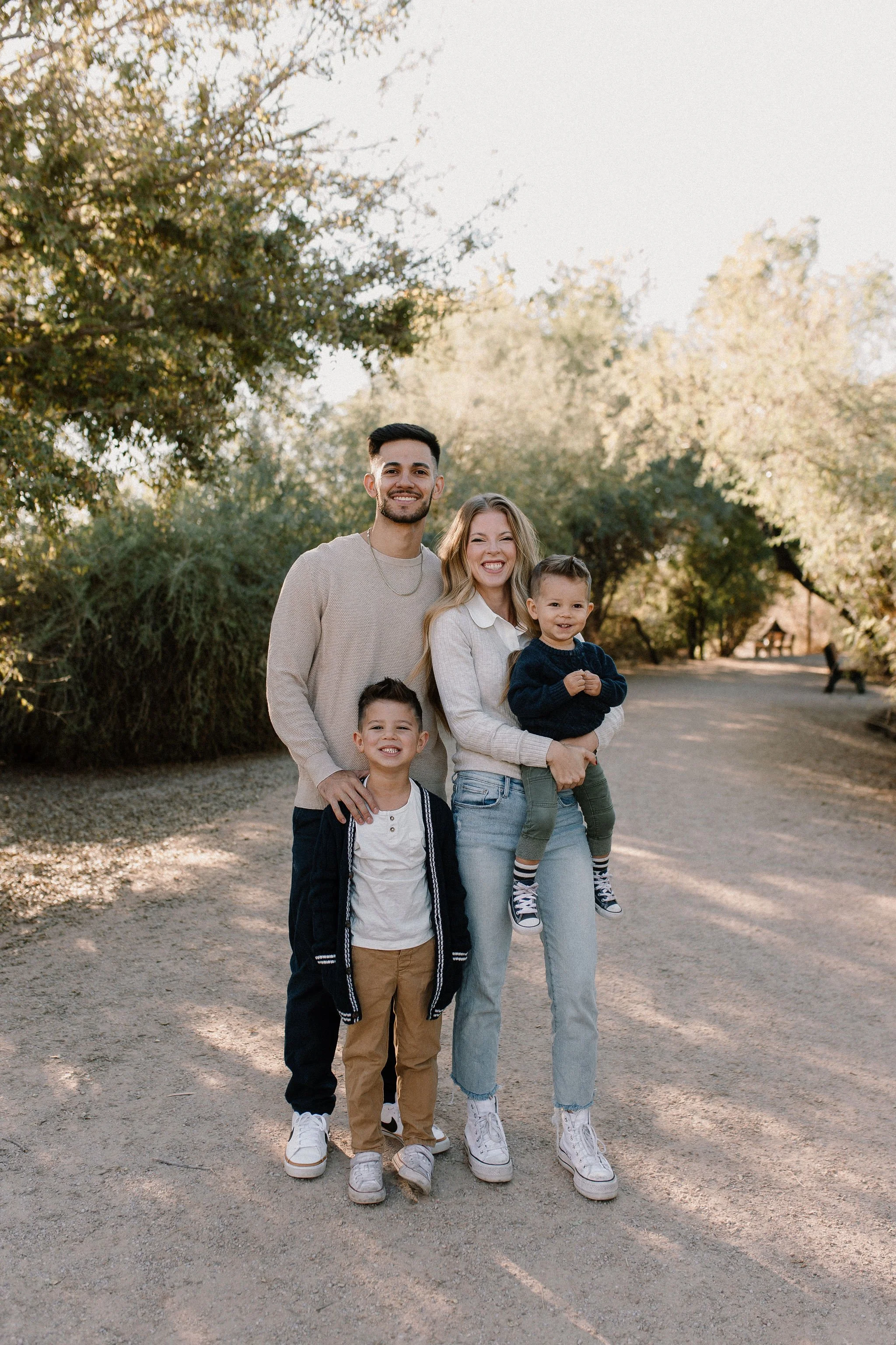 family of four standing together smiling during desert greenery extended family photography session