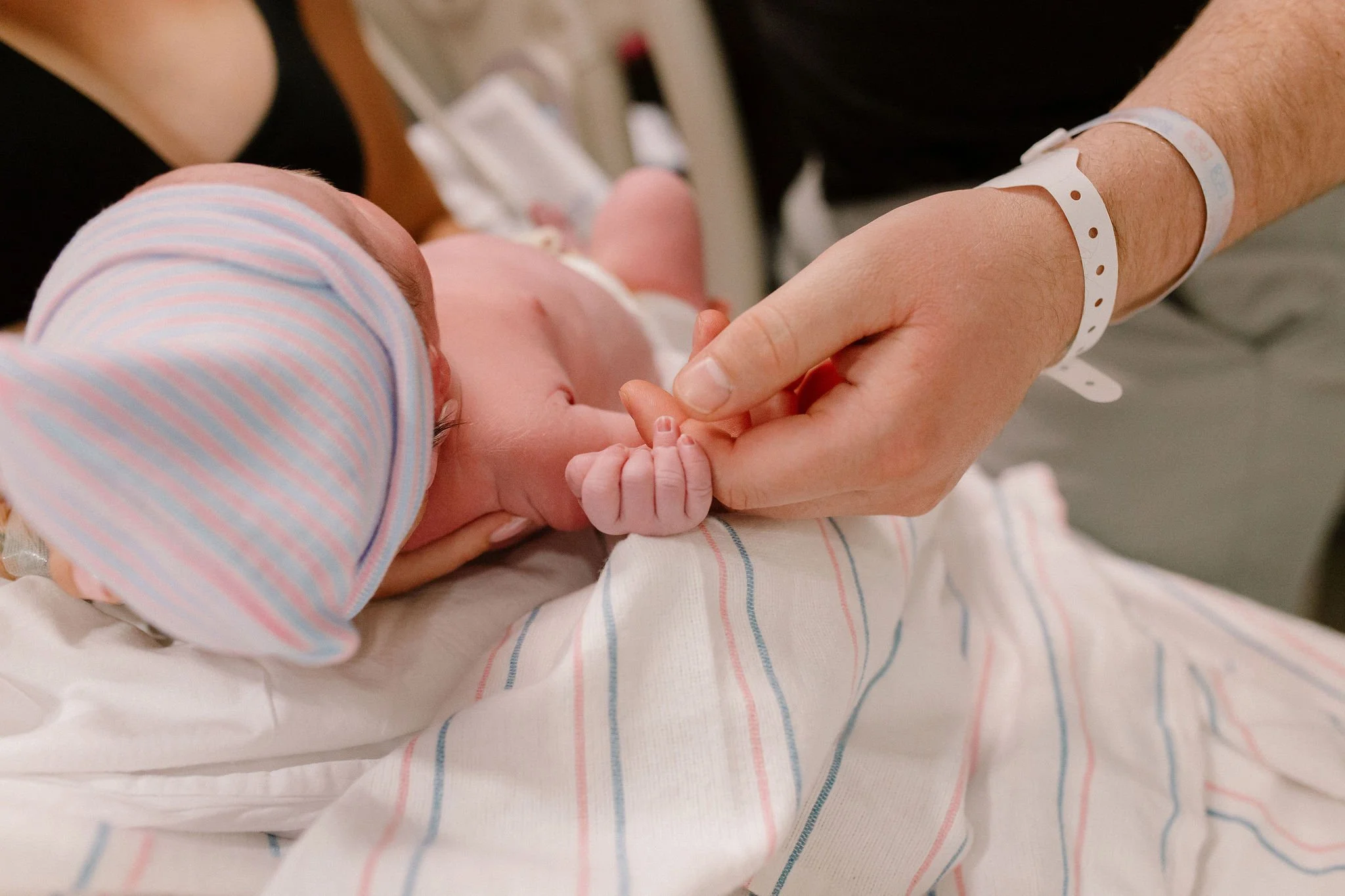 newborn baby holding dad's finger in birth photography session