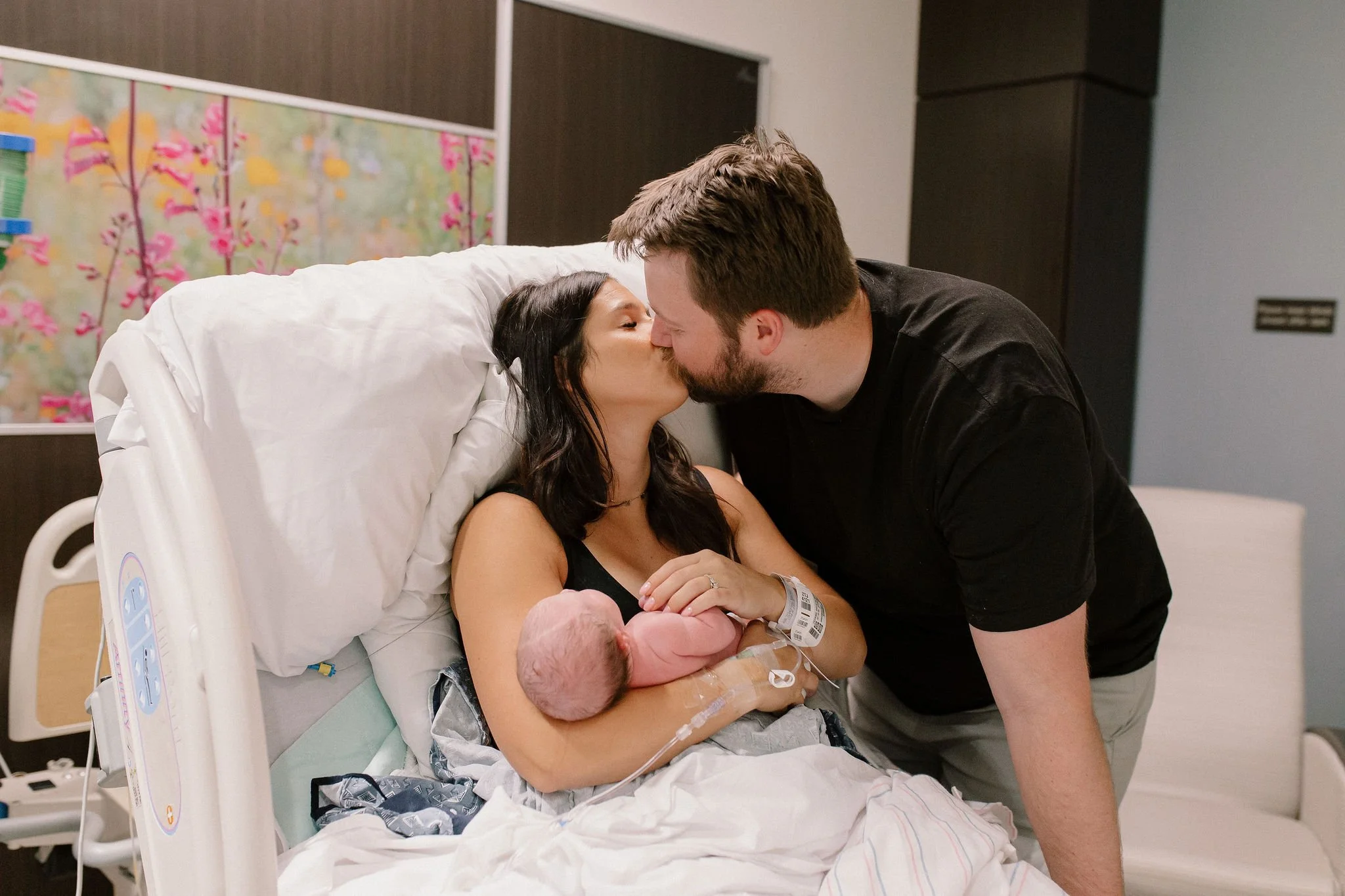 mom holding newborn baby kissing dad in labor and delivery birth photography Gilbert AZ