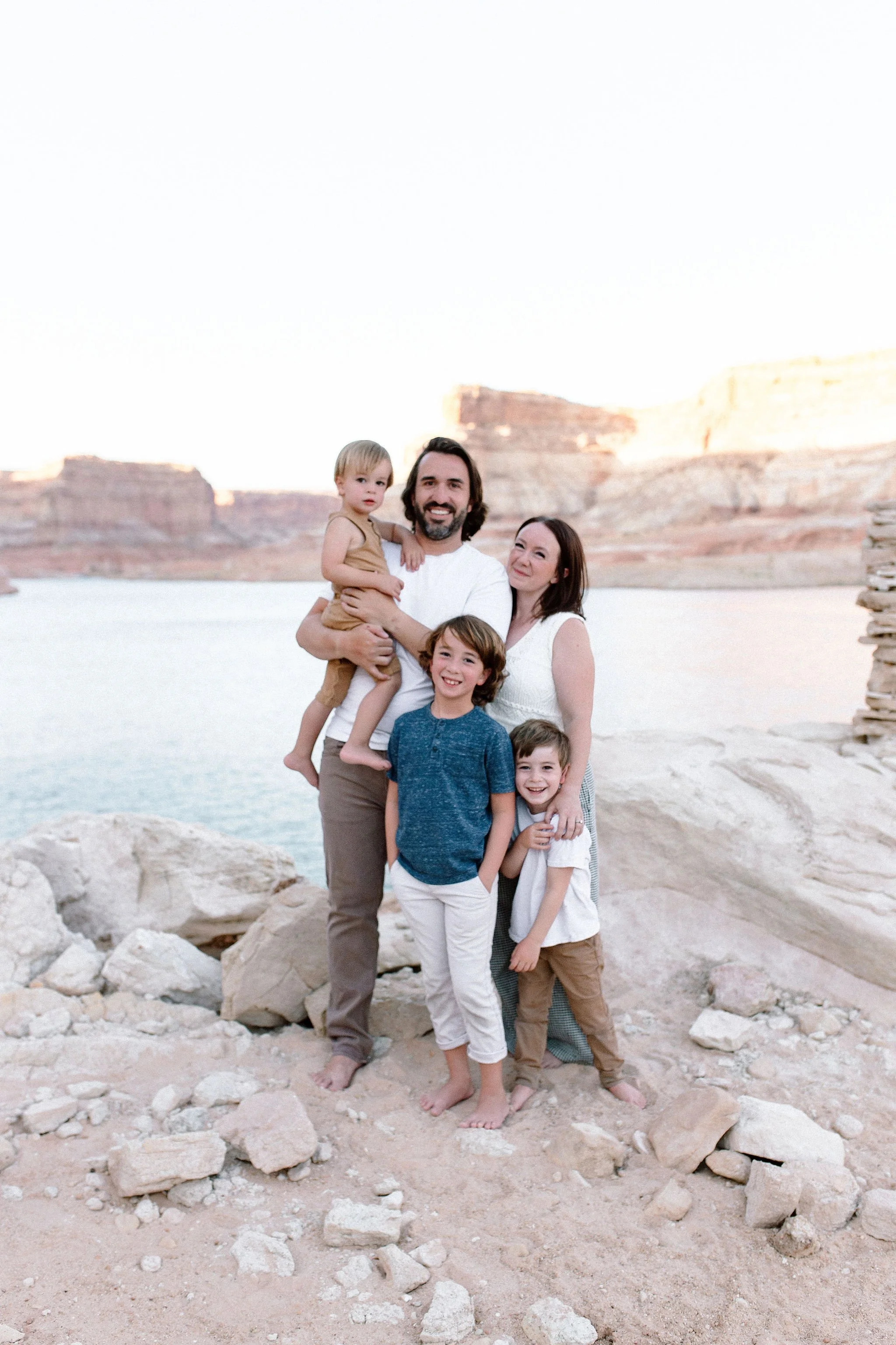 family standing together in Lake Powell smiling at the camera in neutral outfits