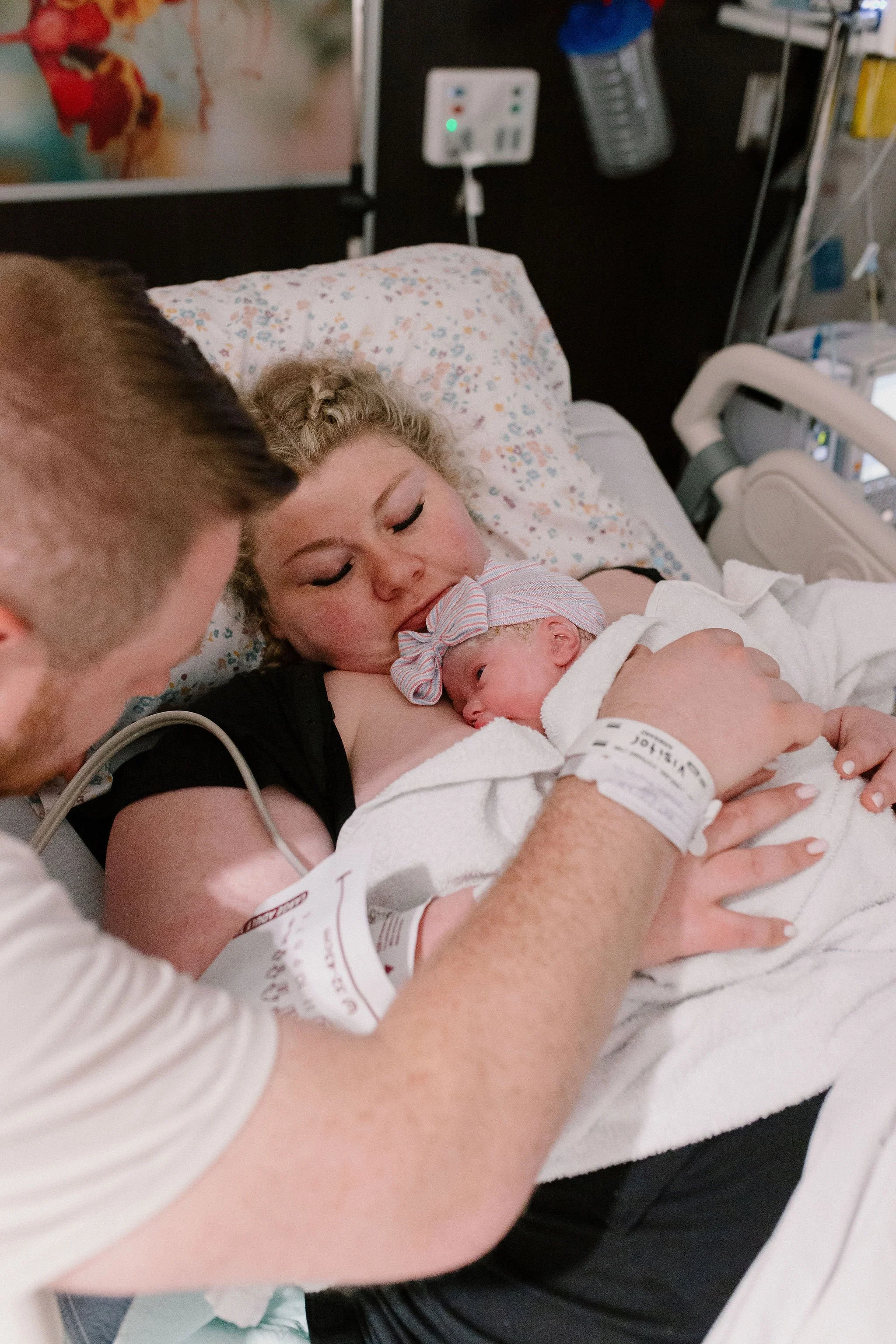 mom holding newborn baby with dad supporting immediately after delivery captured by Mesa birth photographer