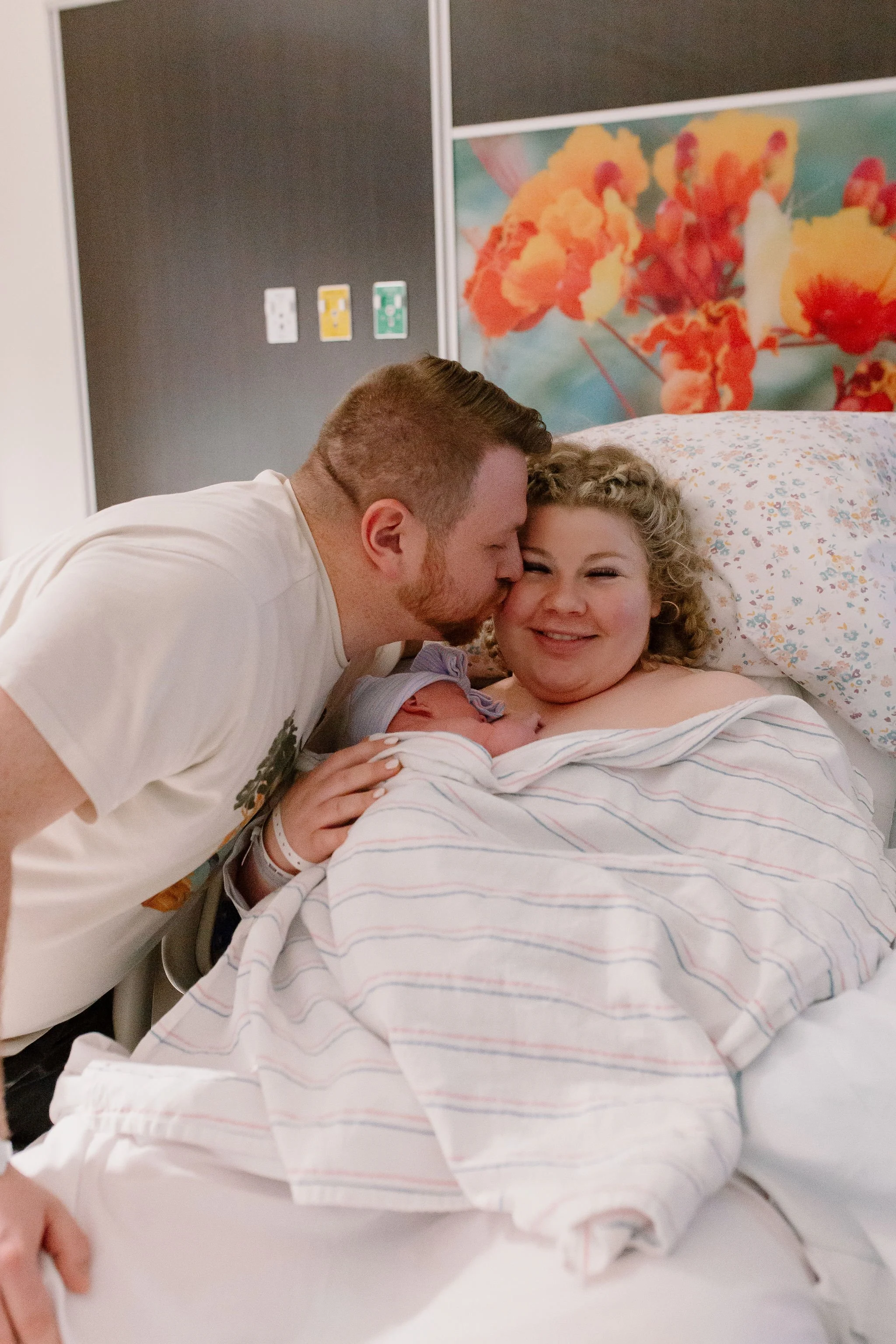 dad kissing mom's cheek holding newborn baby during golden hour captured by Mesa birth photographer