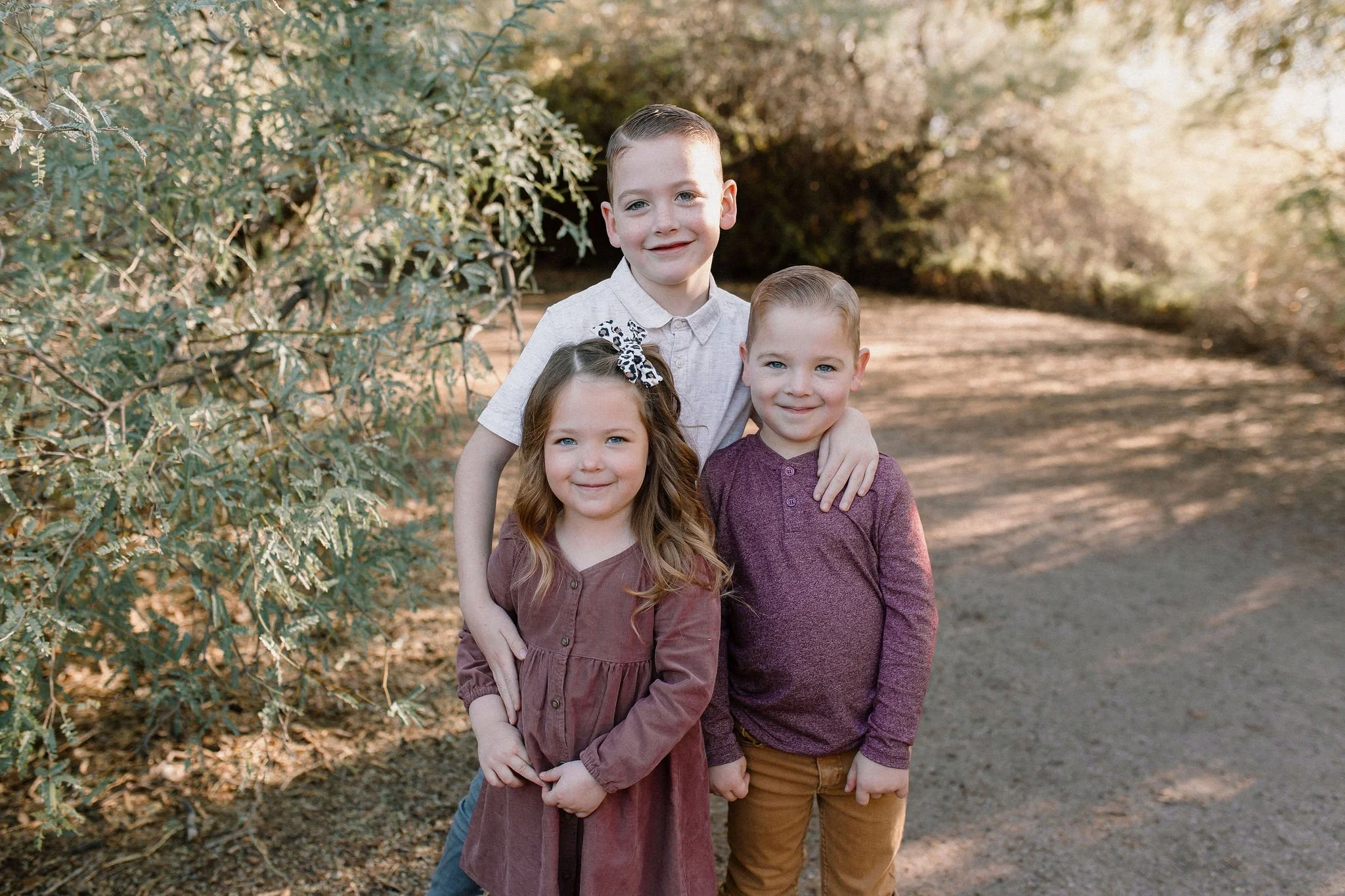 siblings standing together smiling in desert greenery at Gilbert Riparian Preserve
