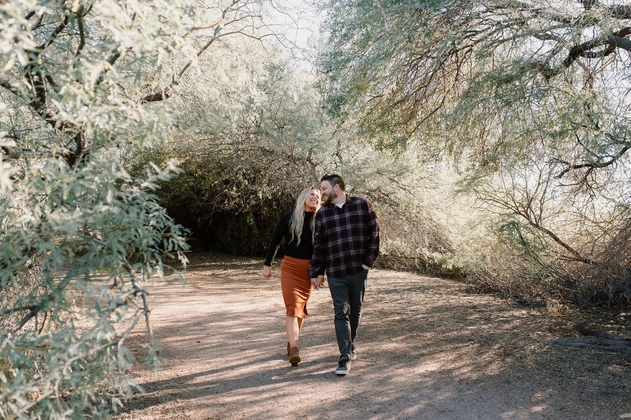 mom and dad walking and holding hands during family photo session at Gilbert Riparian Preserve