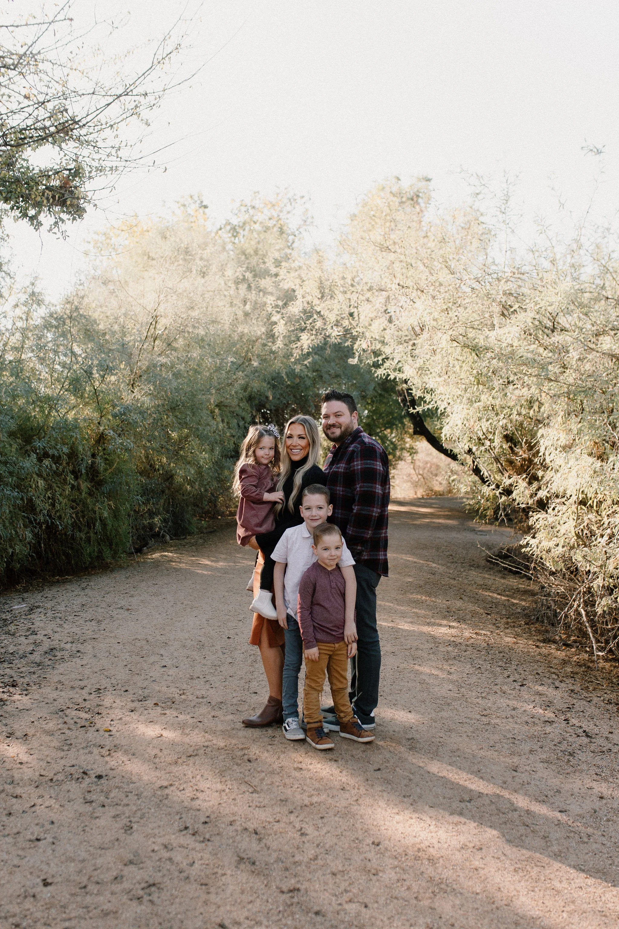 family standing close together smiling in desert greenery at Gilbert Riparian Preserve