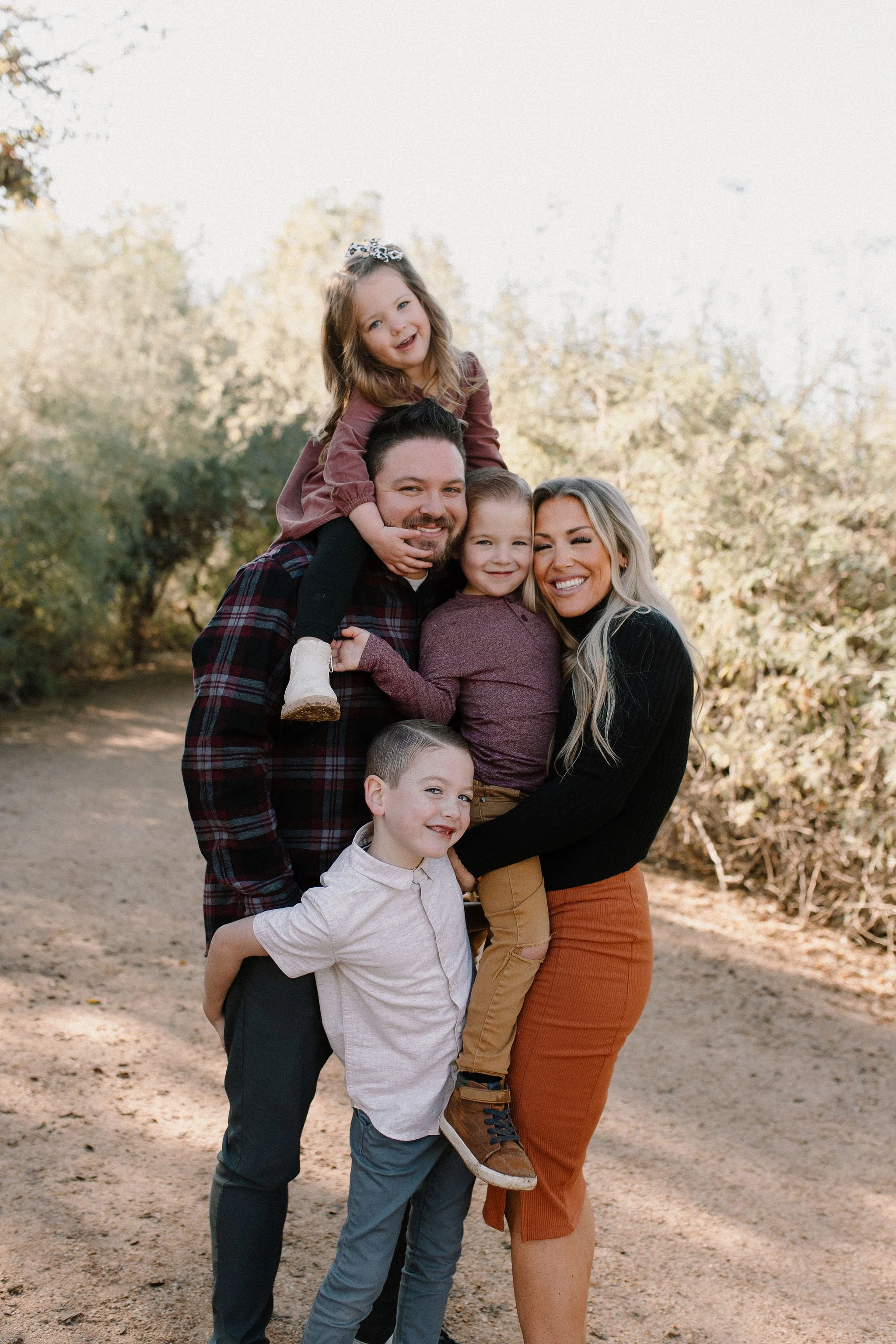 family standing close together smiling and hugging during family photo session at Gilbert Riparian Preserve in Arizona