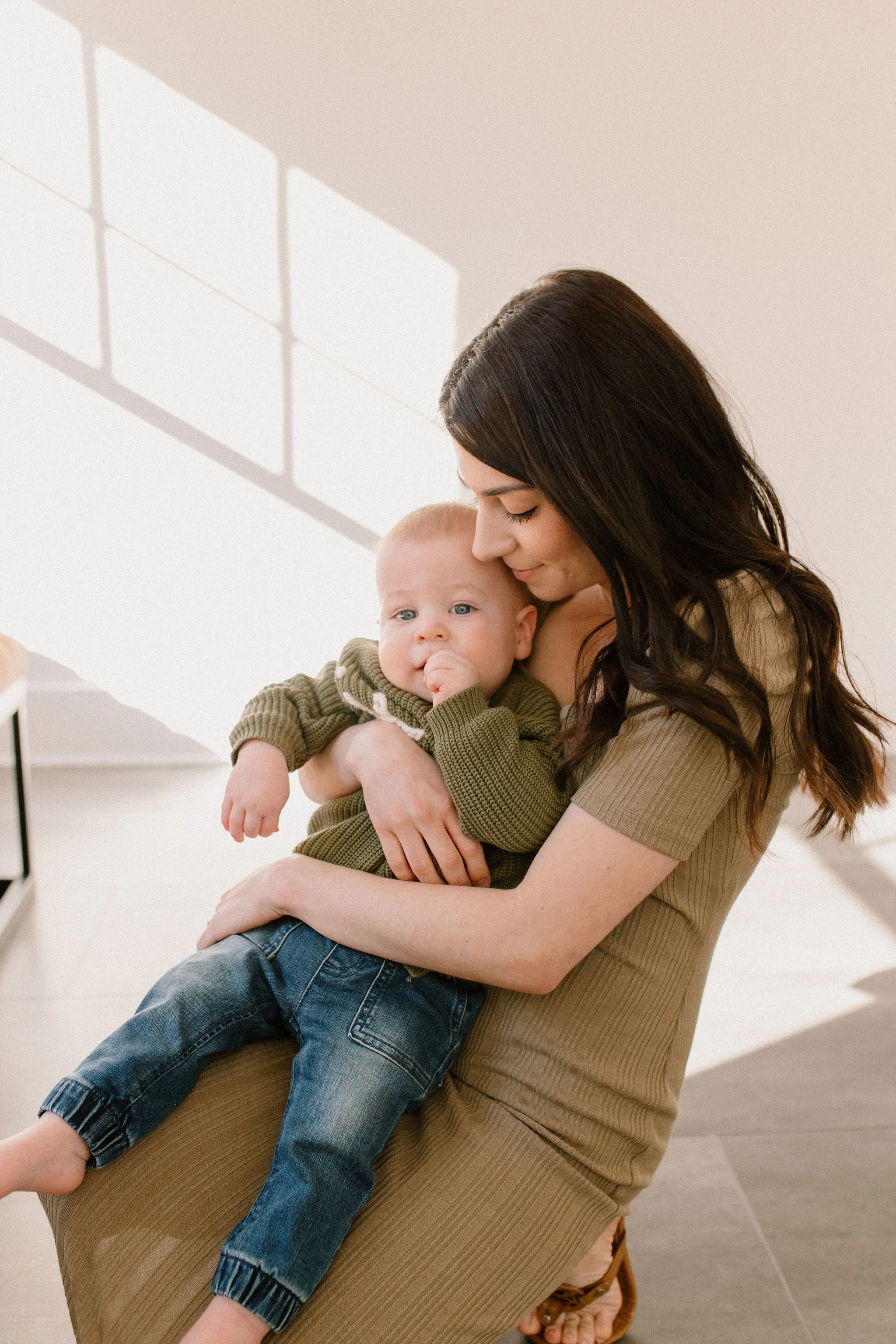 mom holding baby boy in neutral studio setting