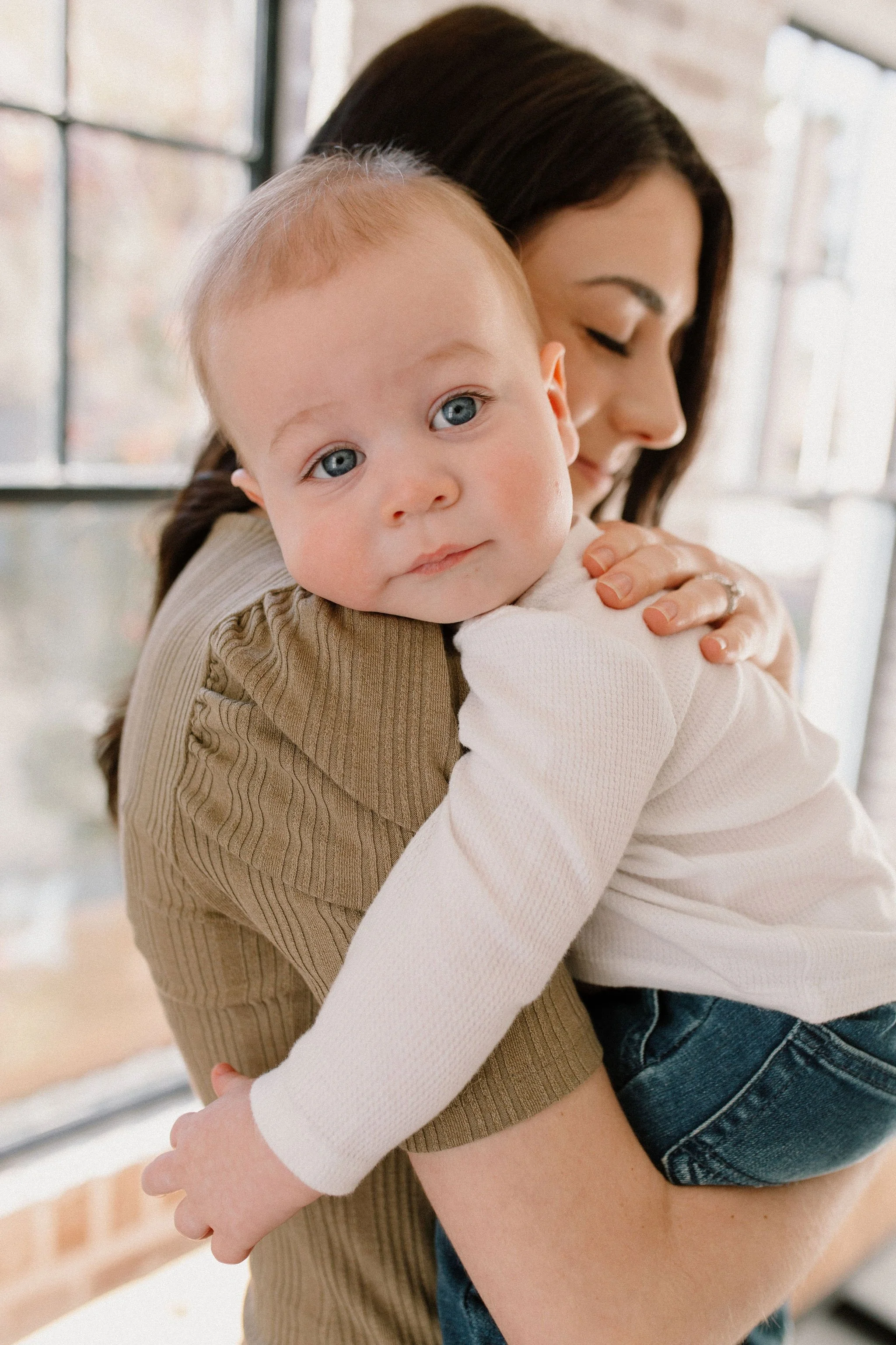 baby boy laying on mom's shoulder in neutral studio family session in Phoenix, Arizona