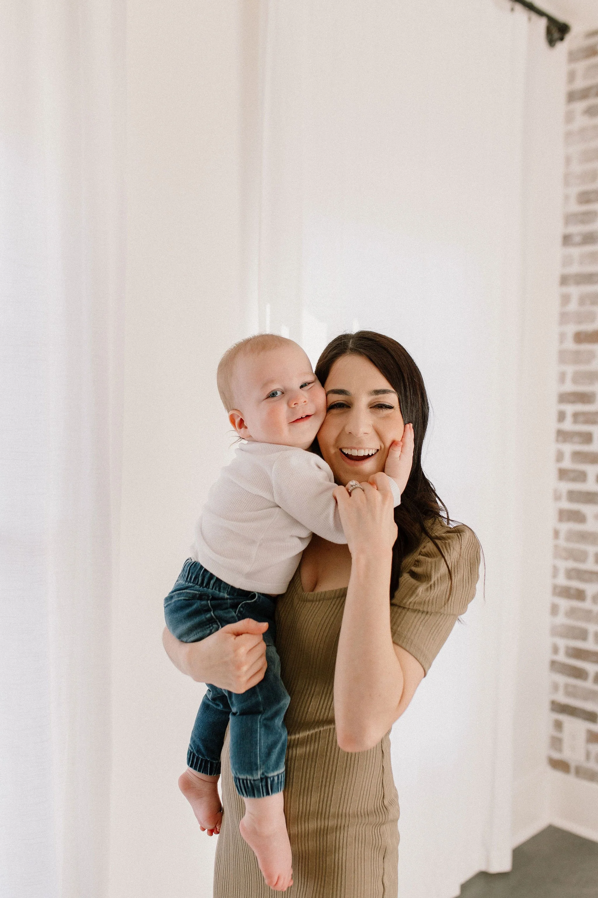 baby boy hugging mom's face during family photo session in neutral studio in Phoenix, Arizona