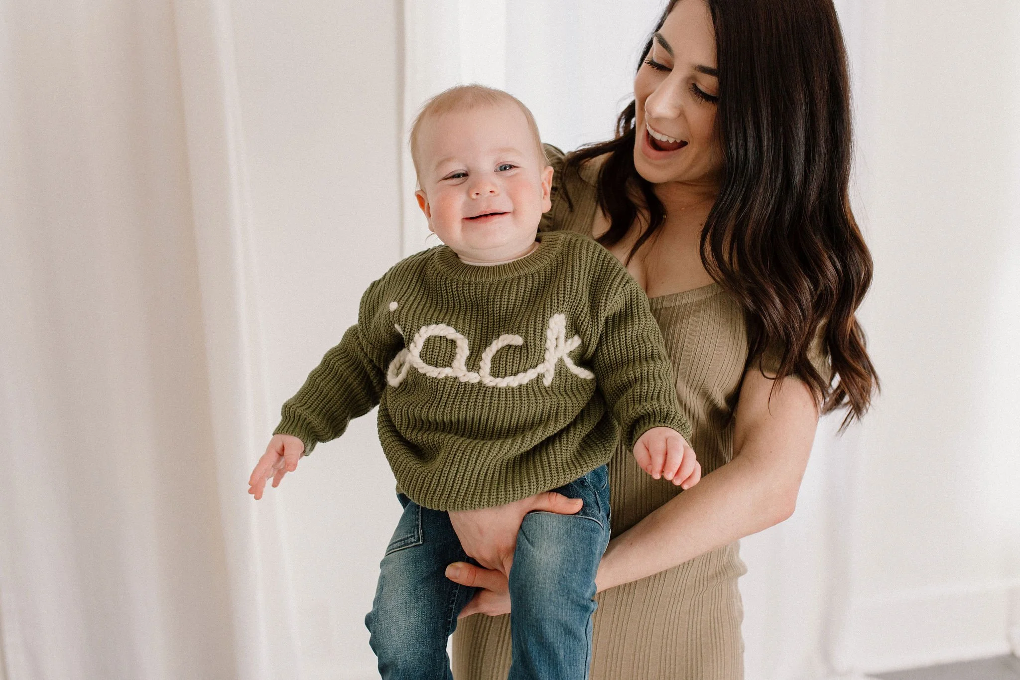 mom holding smiling baby boy in neutral studio in Phoenix, AZ