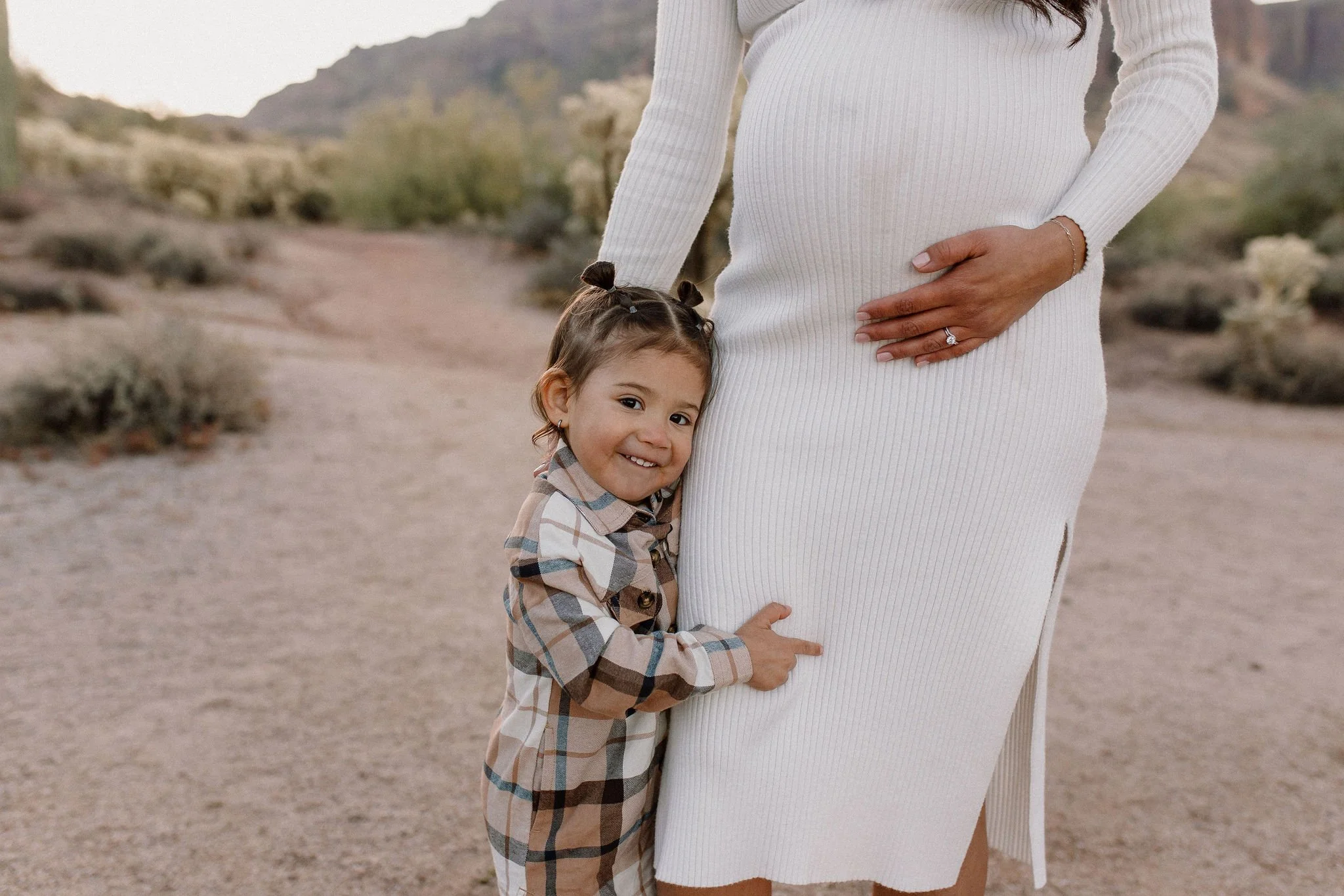 toddler cuddling with pregnant mom's belly in desert family maternity pics in Lost Dutchman State Park