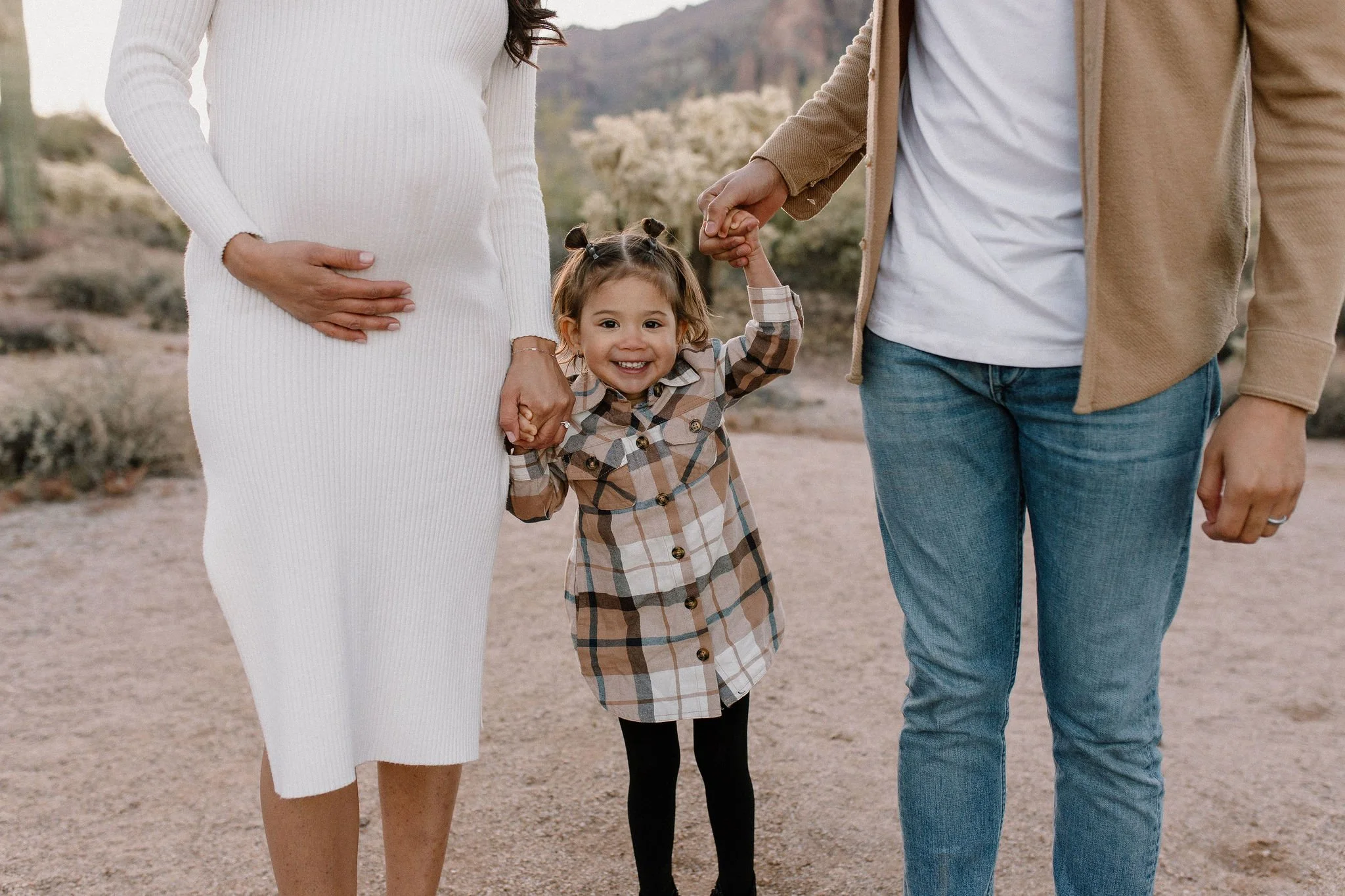 pregnant mom holding belly and toddler holding dad's hand in desert family maternity pics in Lost Dutchman State Park
