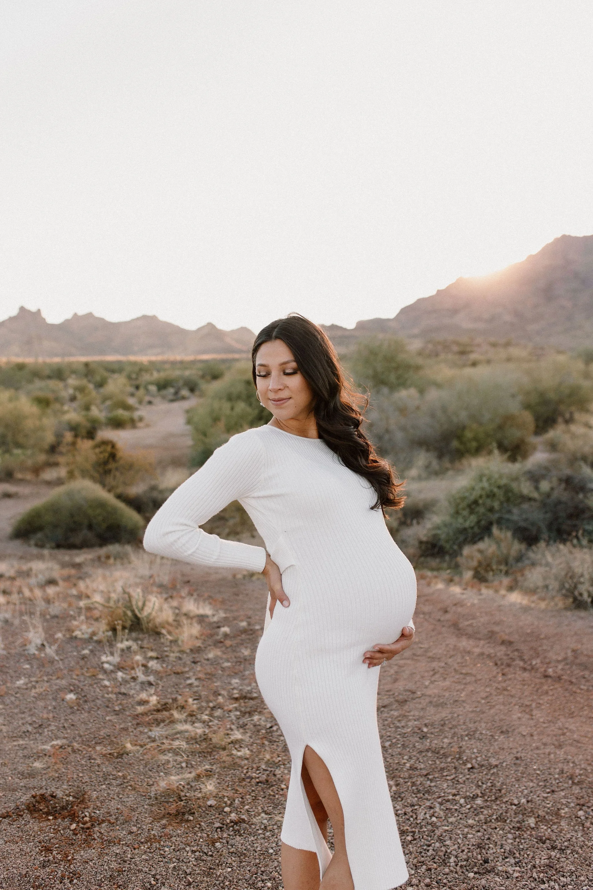 pregnant mom holding belly in desert family maternity pics in Lost Dutchman State Park