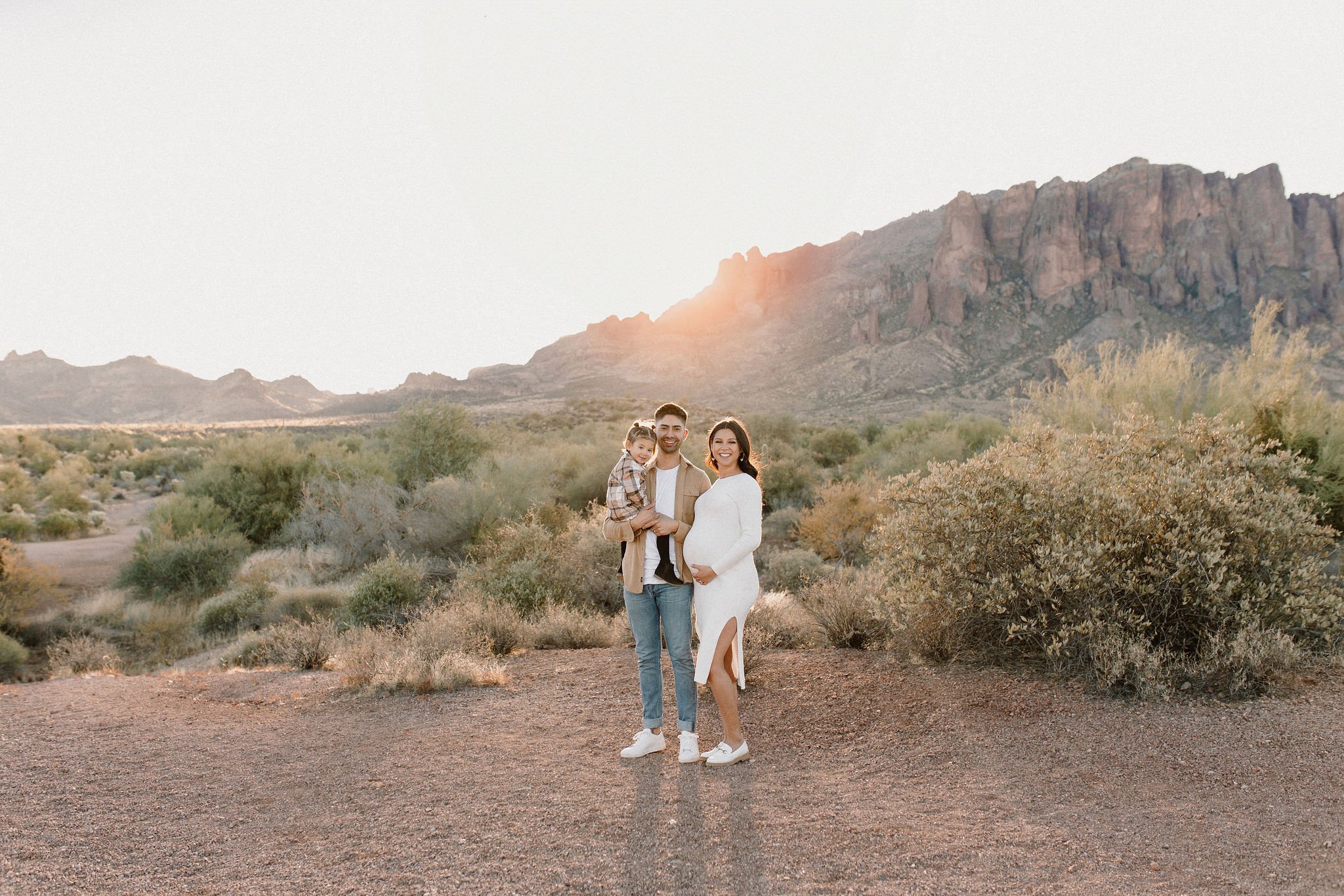 family standing and smiling in desert family maternity pics in Lost Dutchman State Park