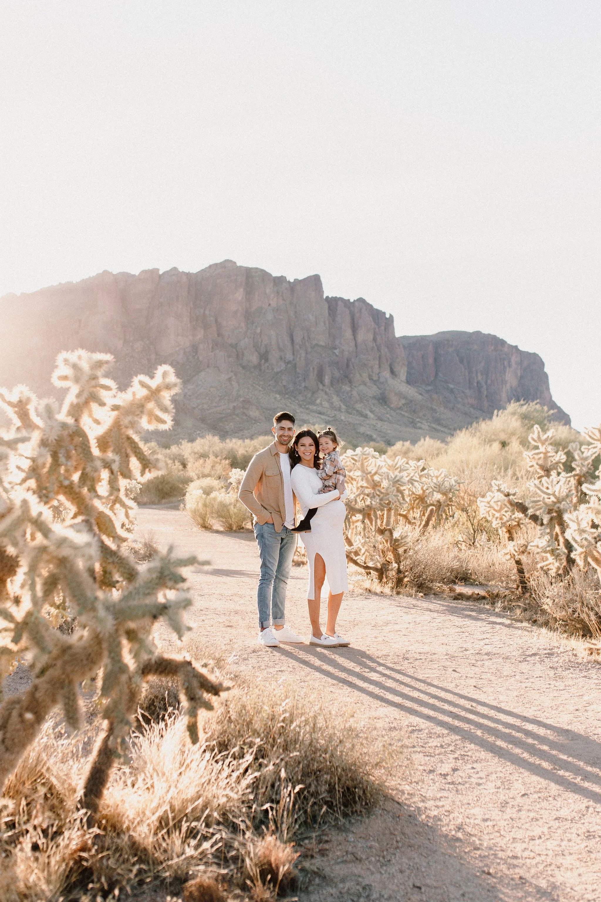family standing and smiling in desert family maternity pics in Lost Dutchman State Park