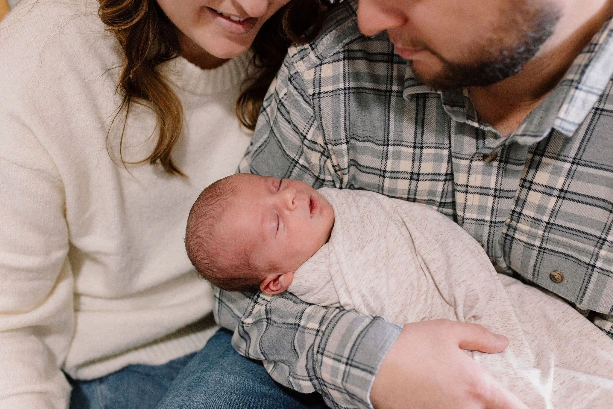 mom and dad holding swaddled newborn baby