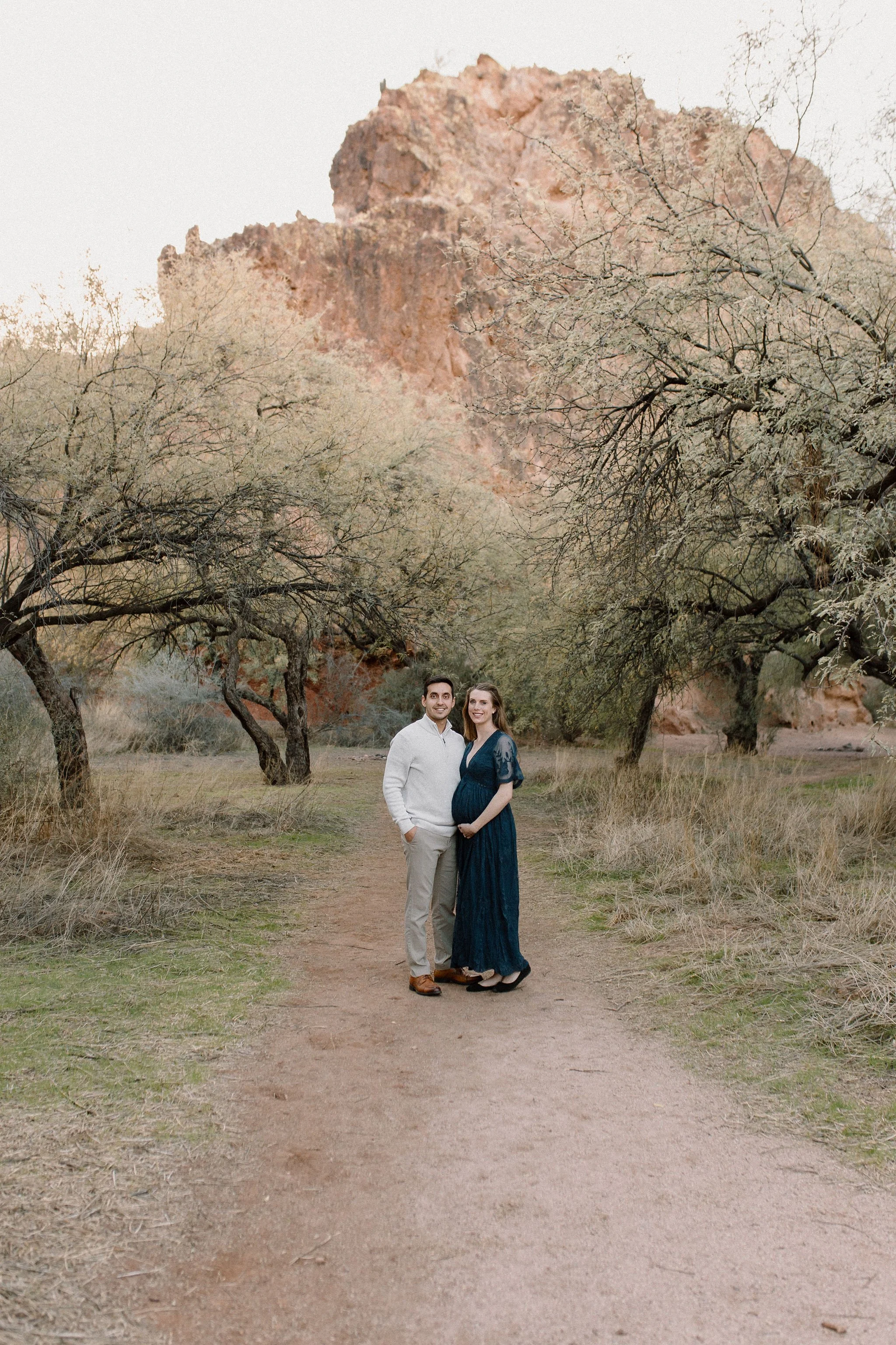 pregnant mom and dad standing together smiling in Mesa desert maternity photography session
