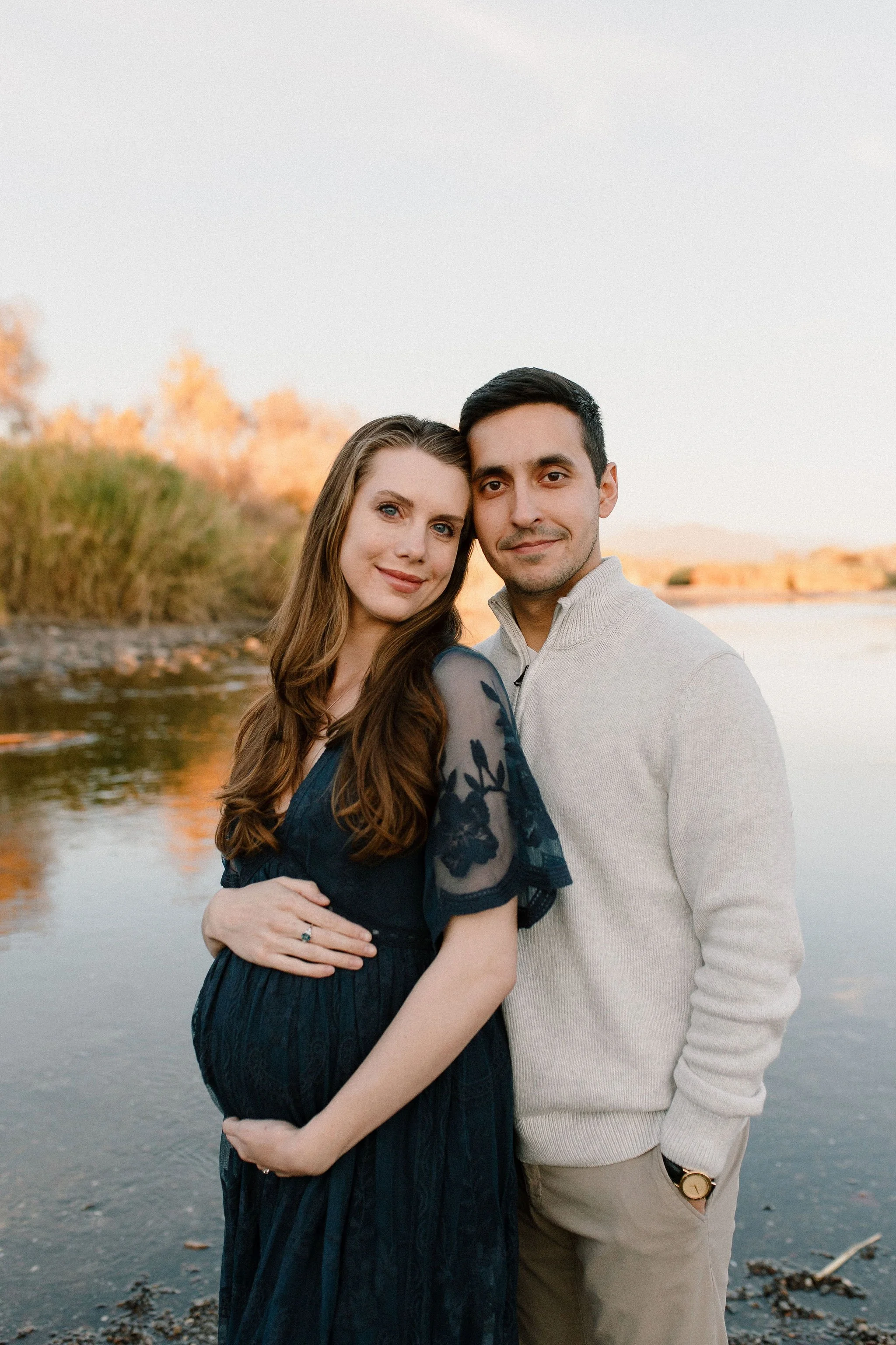 pregnant mom standing with husband in front of Salt River in Mesa maternity photography session