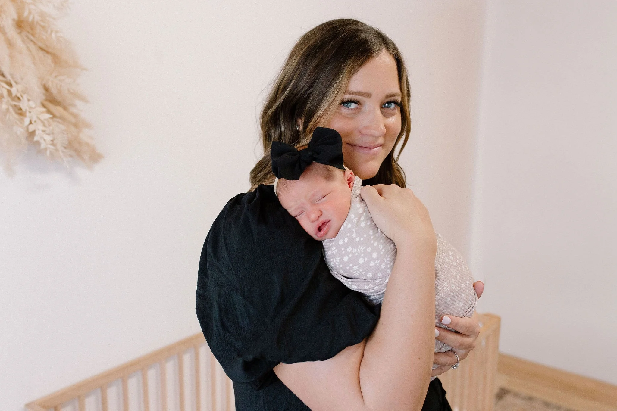 mom holding newborn baby girl in neutral nursery