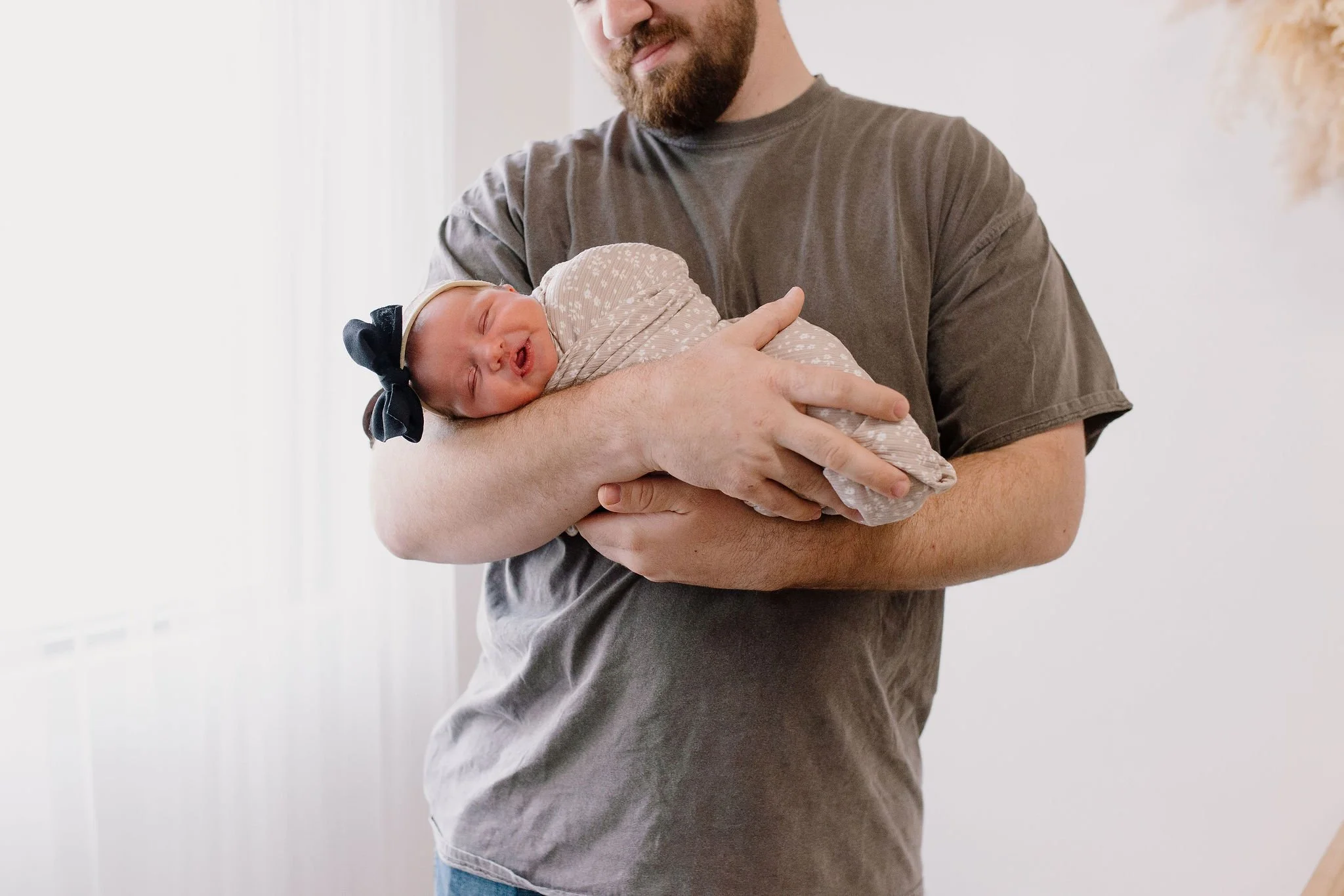 dad holding newborn baby girl in neutral nursery