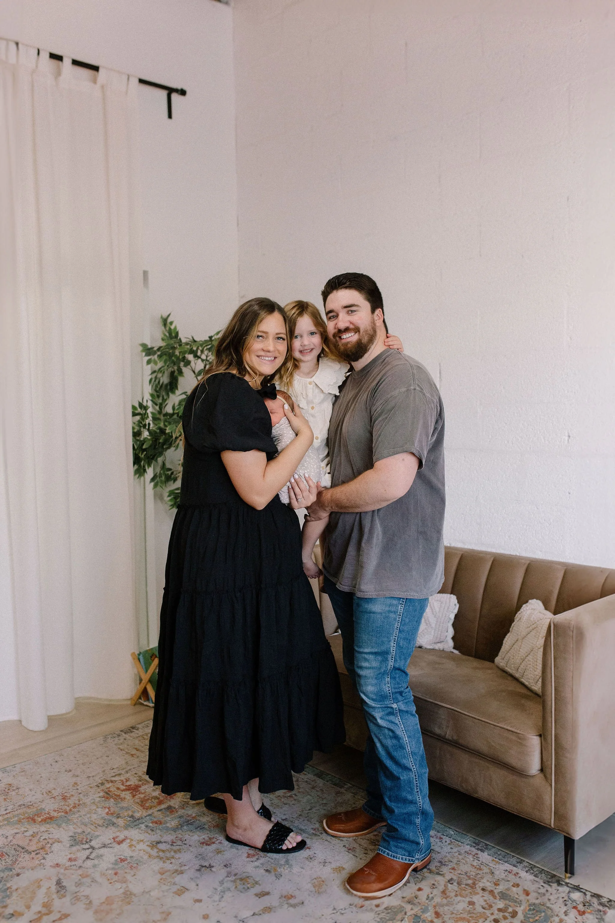 family standing together with newborn baby in neutral studio nursery