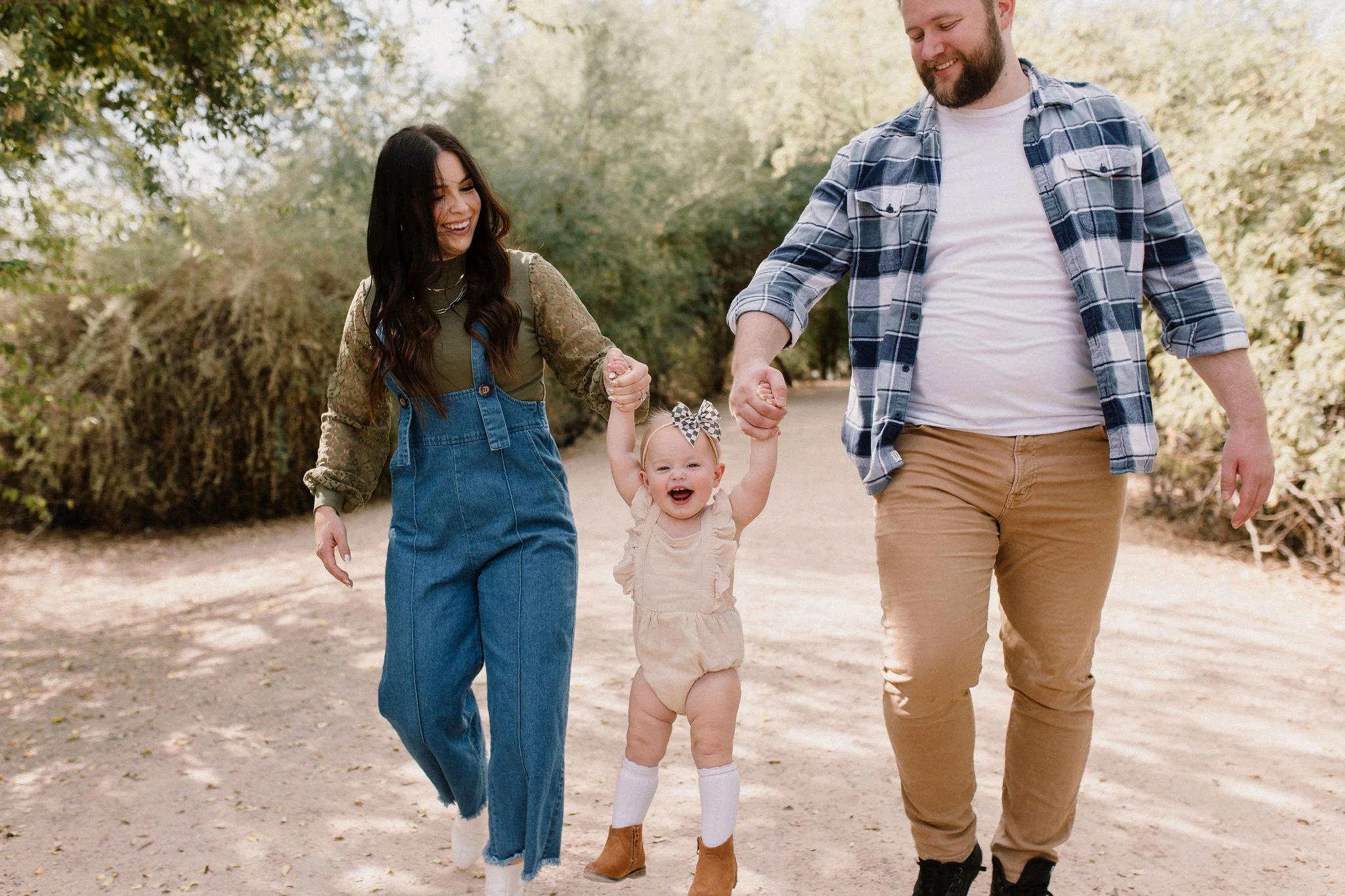mom and dad walking and swinging toddler in desert greenery family photography session