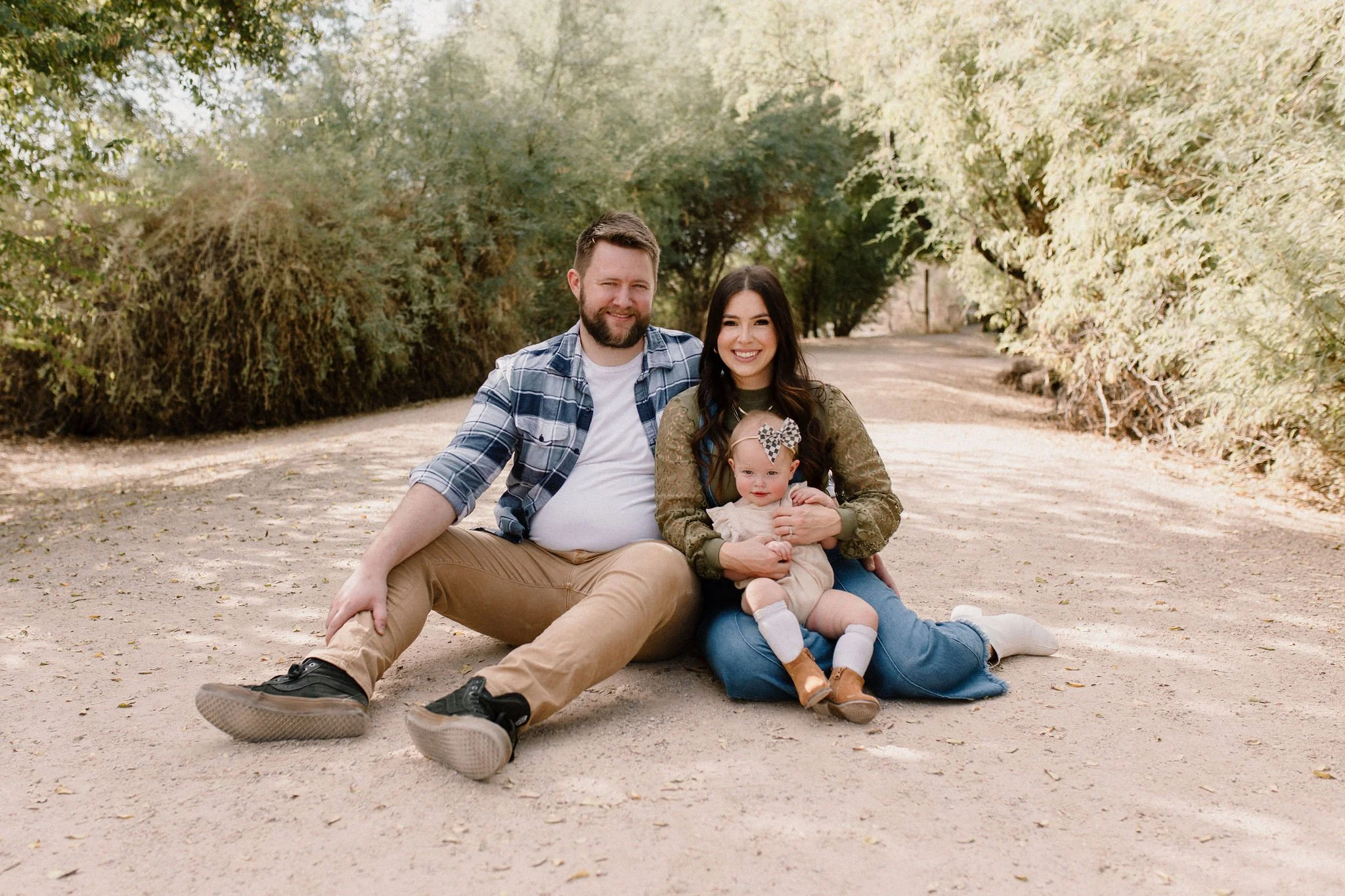 family of three sitting and smiling in desert greenery family photography session