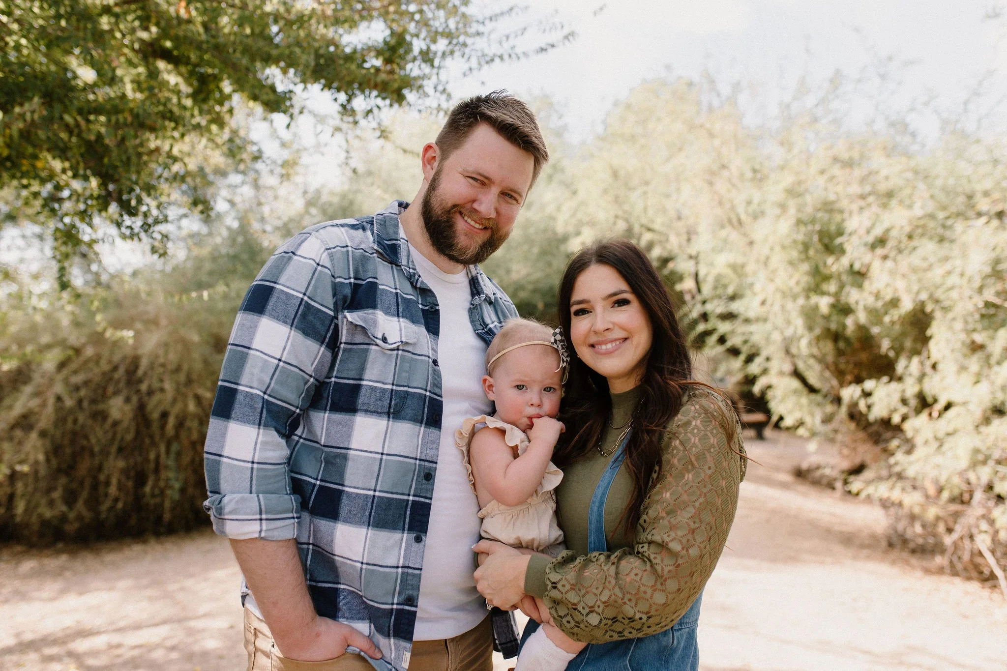 family of three standing and smiling in desert greenery photography session