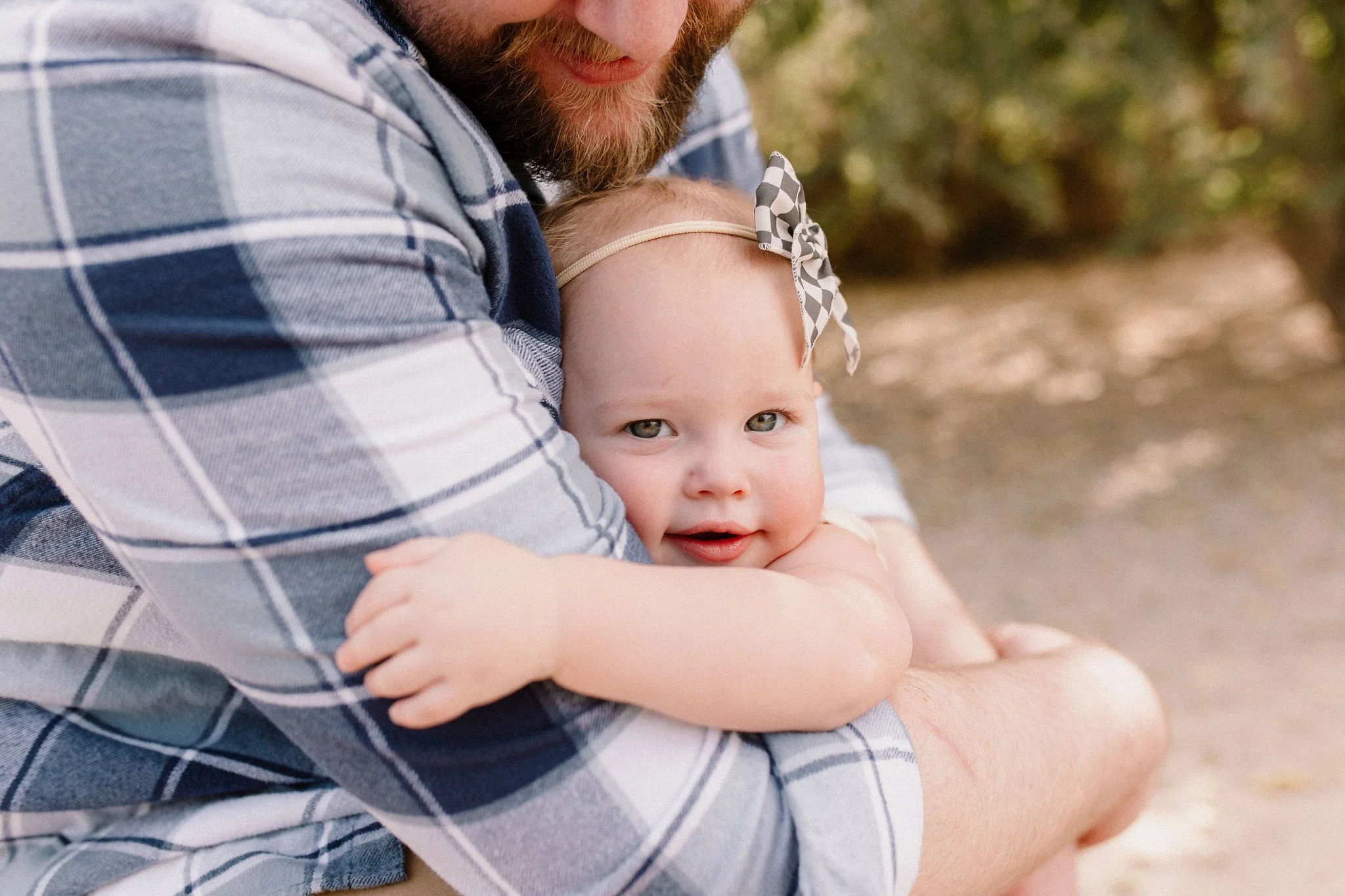 baby girl hugging dad during family photography session in desert greenery