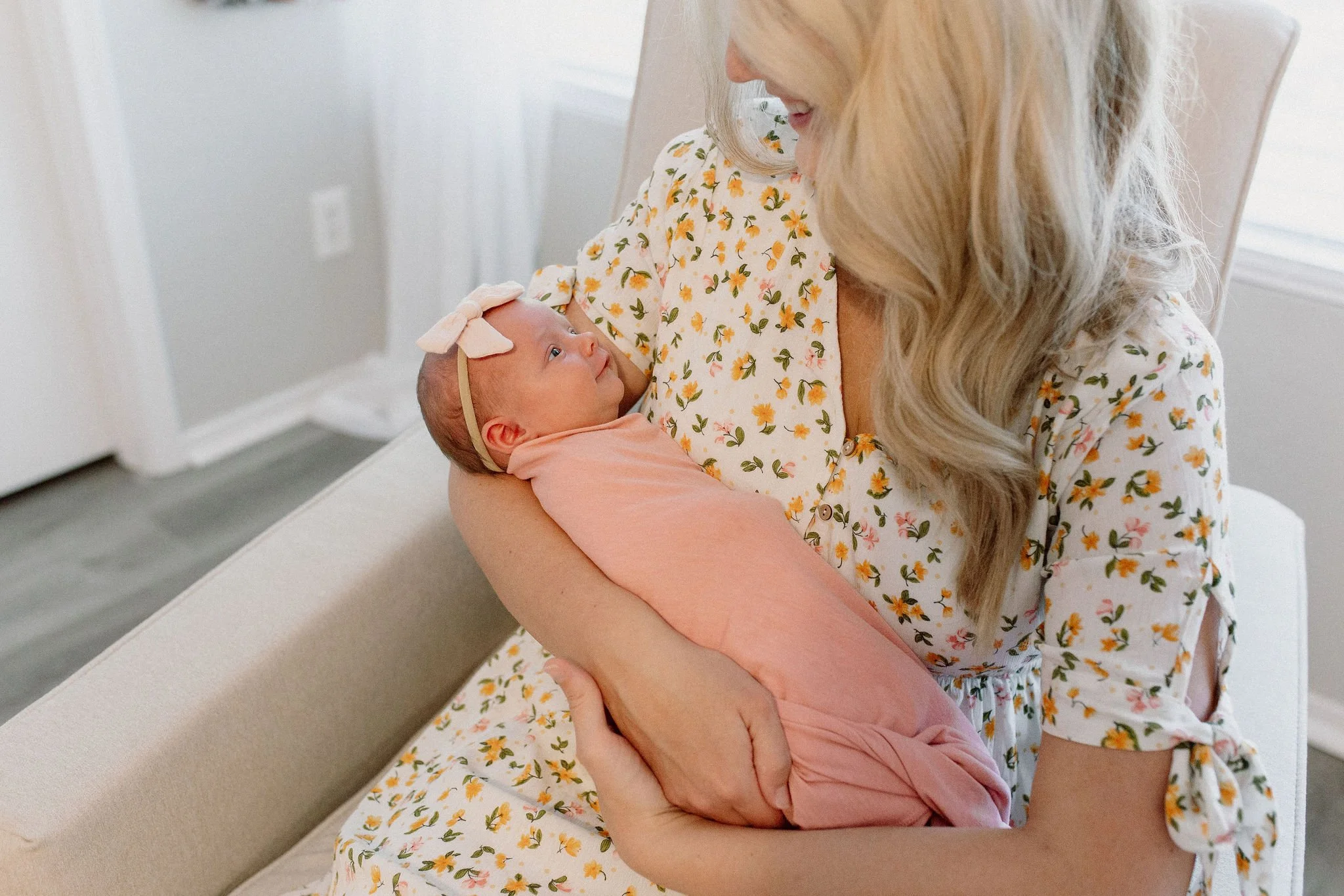 mom holding swaddled newborn baby girl in nursery during lifestyle in-home photography session