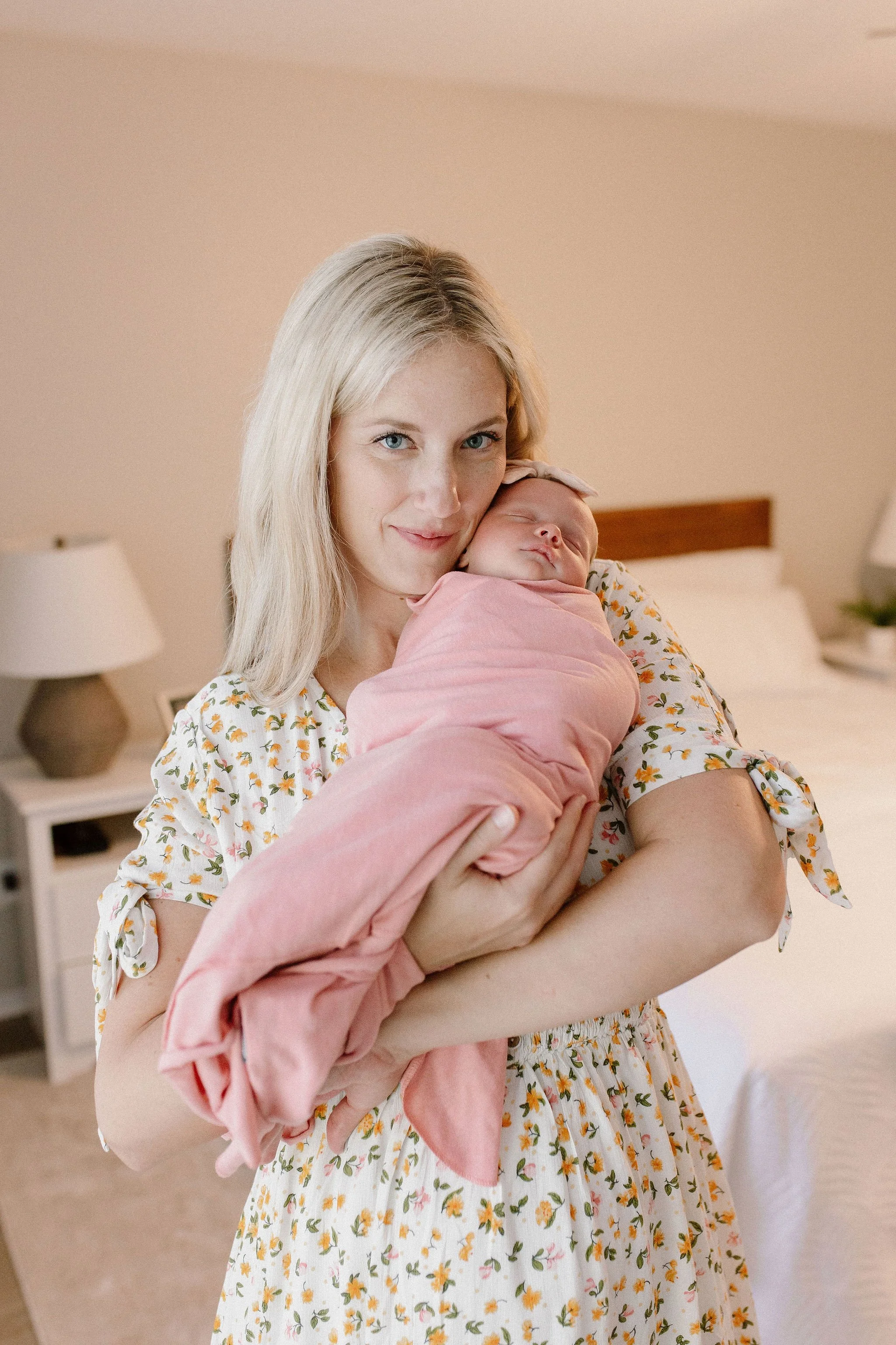mom holding swaddled newborn baby girl in lifestyle in-home newborn photography session