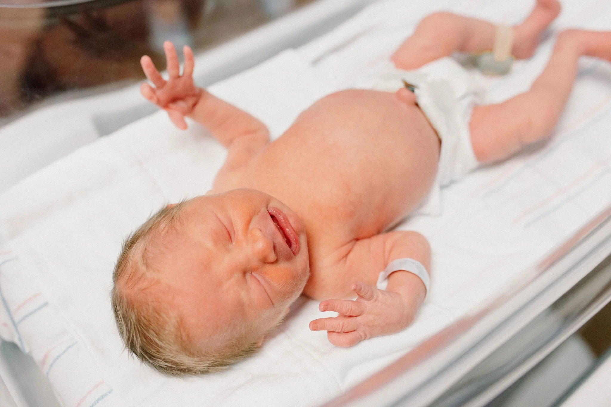 newborn baby boy laying in hospital bassinet after birth