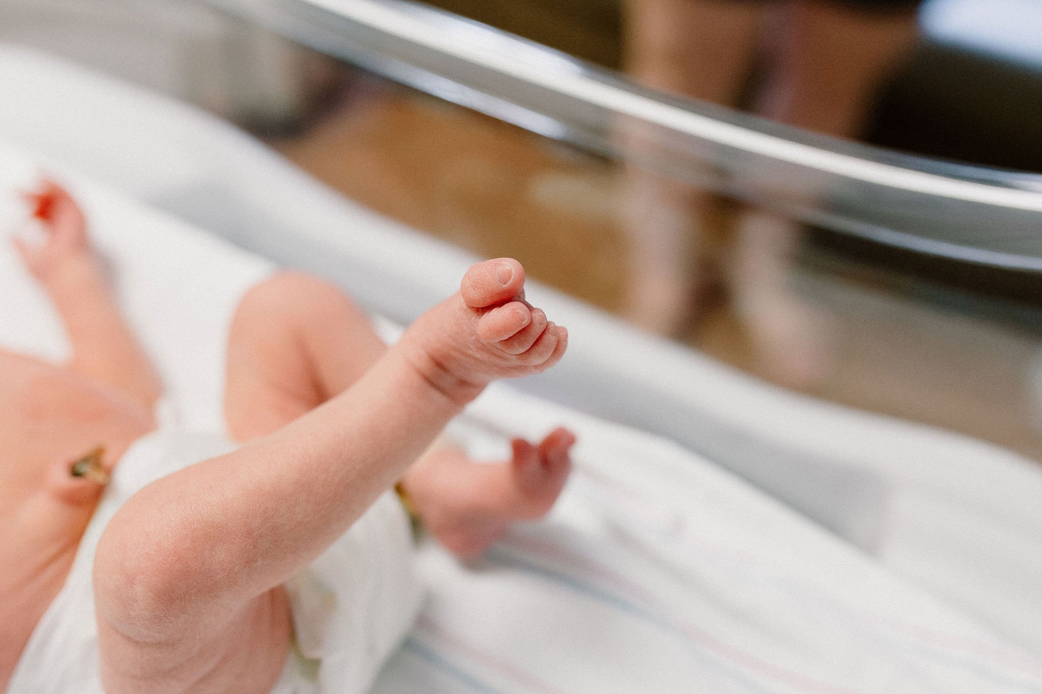 close up details shot of newborn baby toes and feet in hospital room after birth