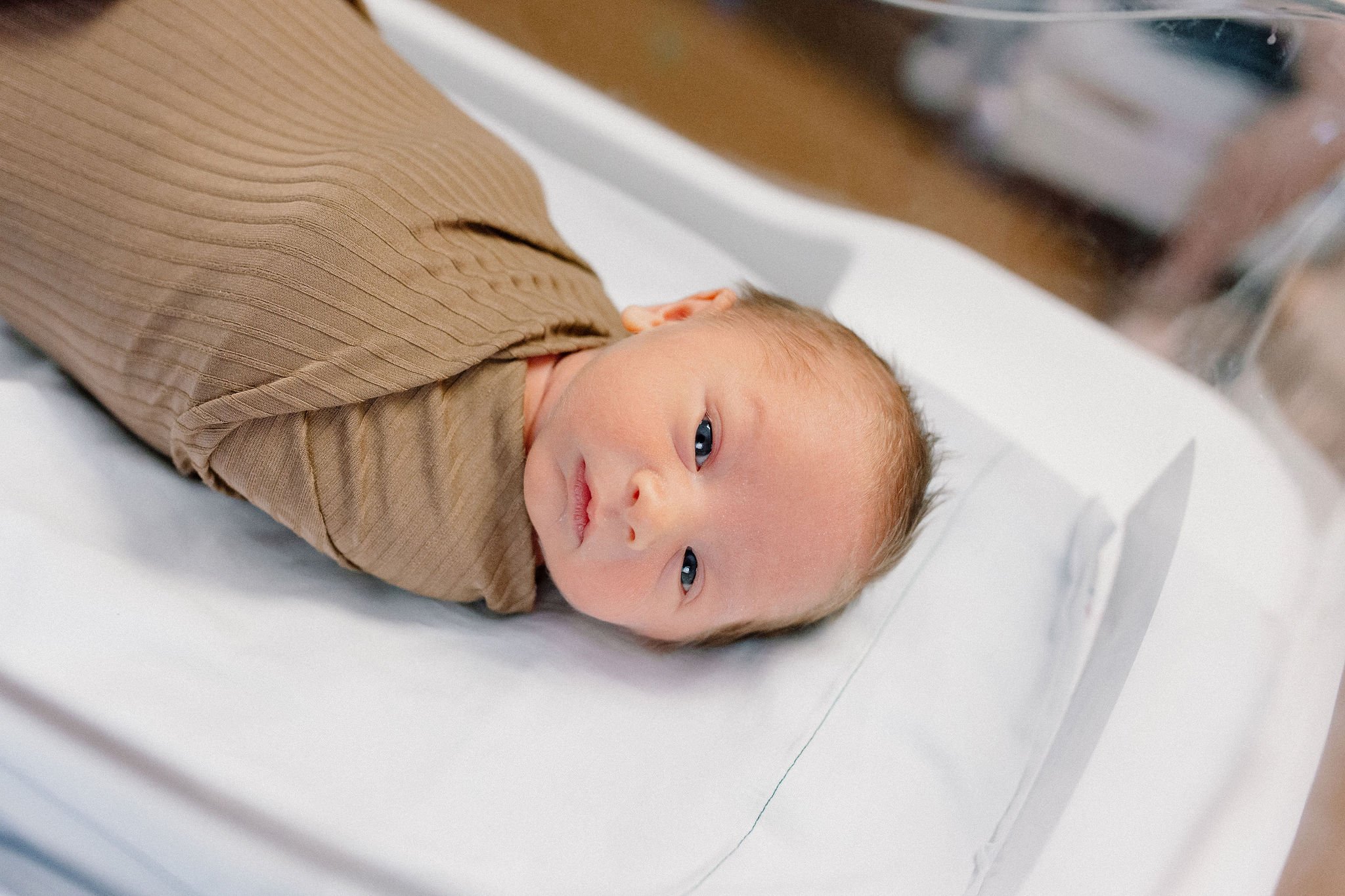 swaddled newborn baby boy in hospital bassinet after birth