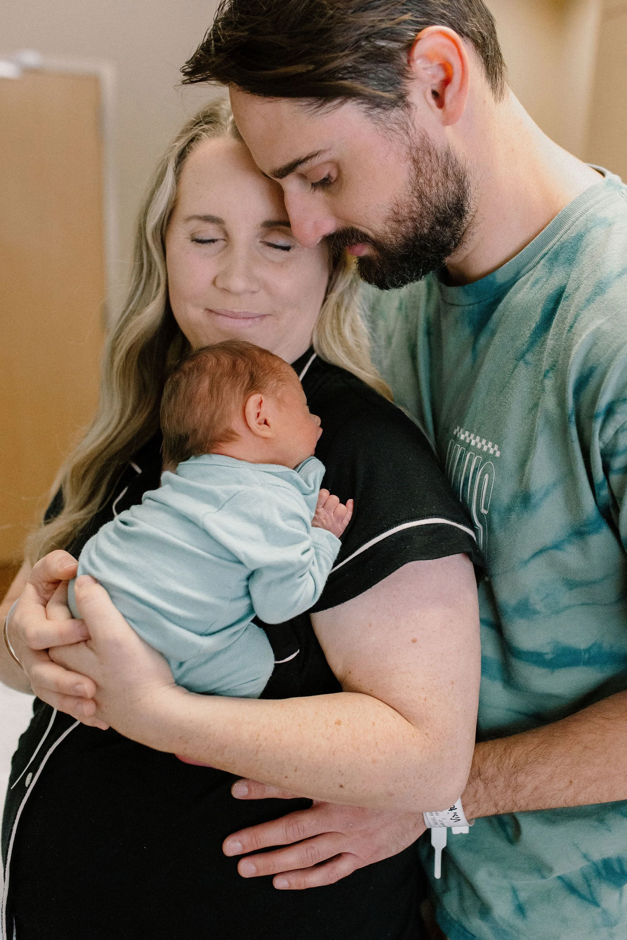 mom and dad cuddling newborn baby boy in the hospital after birth