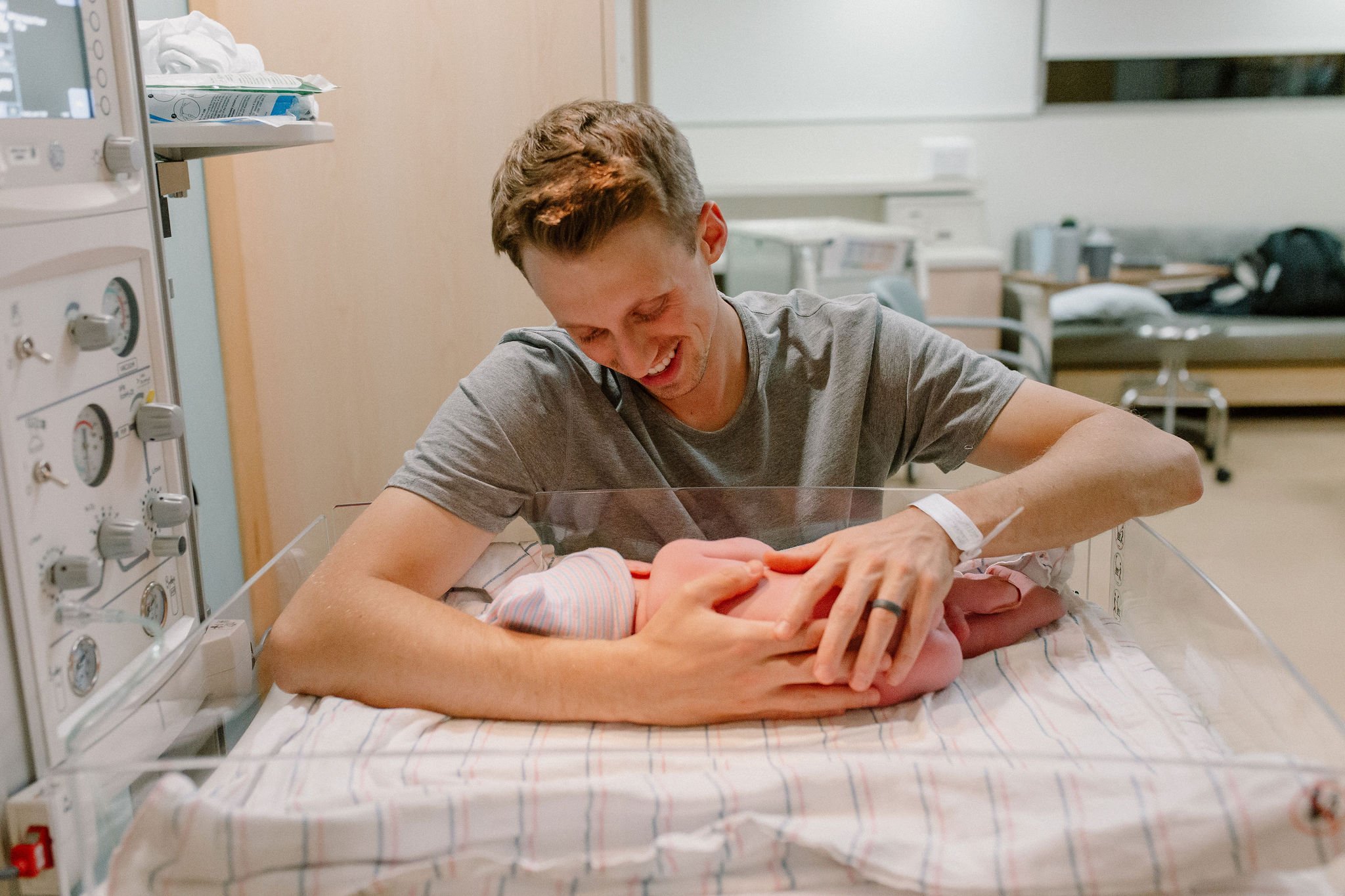 dad holding newborn baby in warmer hospital birth photography