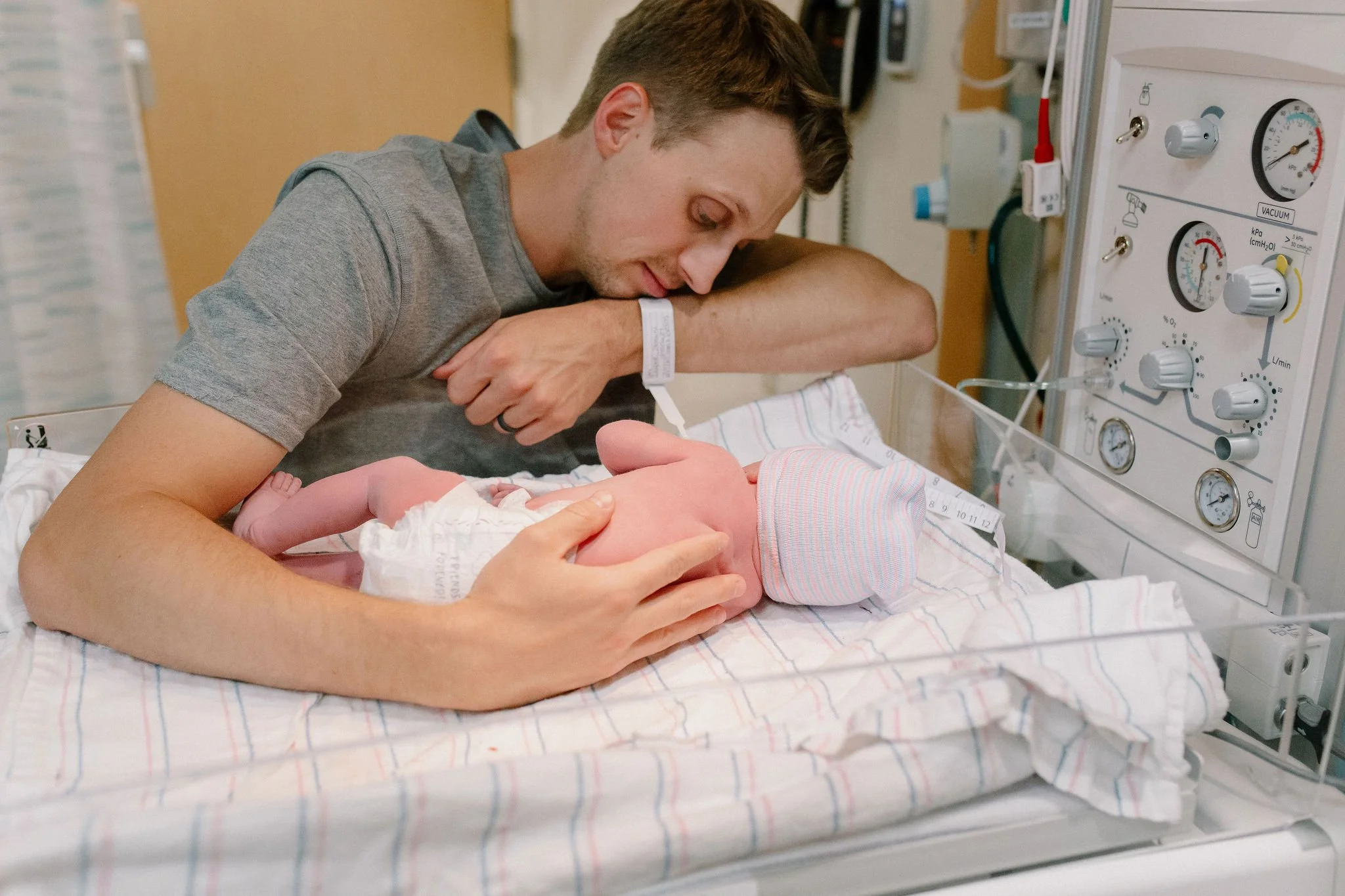dad holding newborn baby in warmer in labor and delivery birth photography Gilbert Arizona
