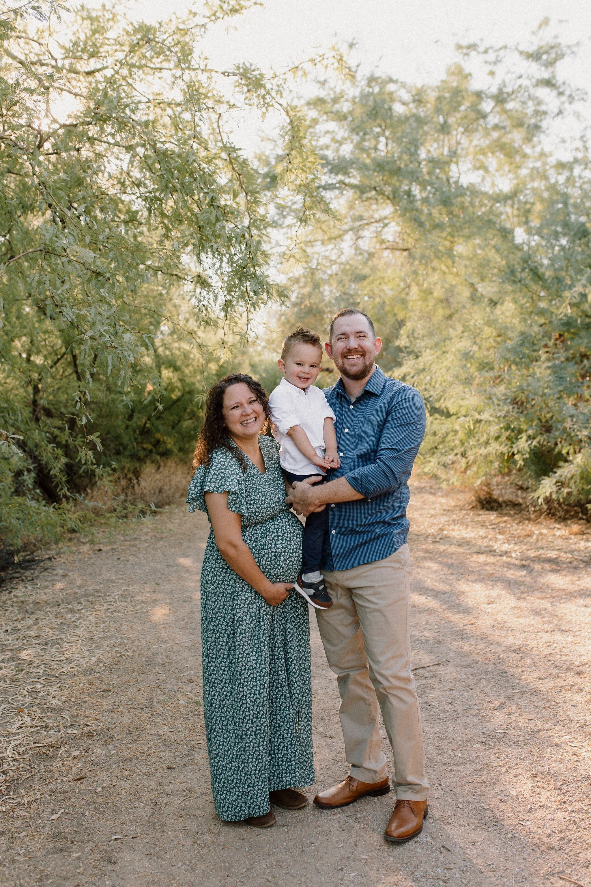 family standing together smiling during family maternity photos at Gilbert Riparian Preserve in Arizona