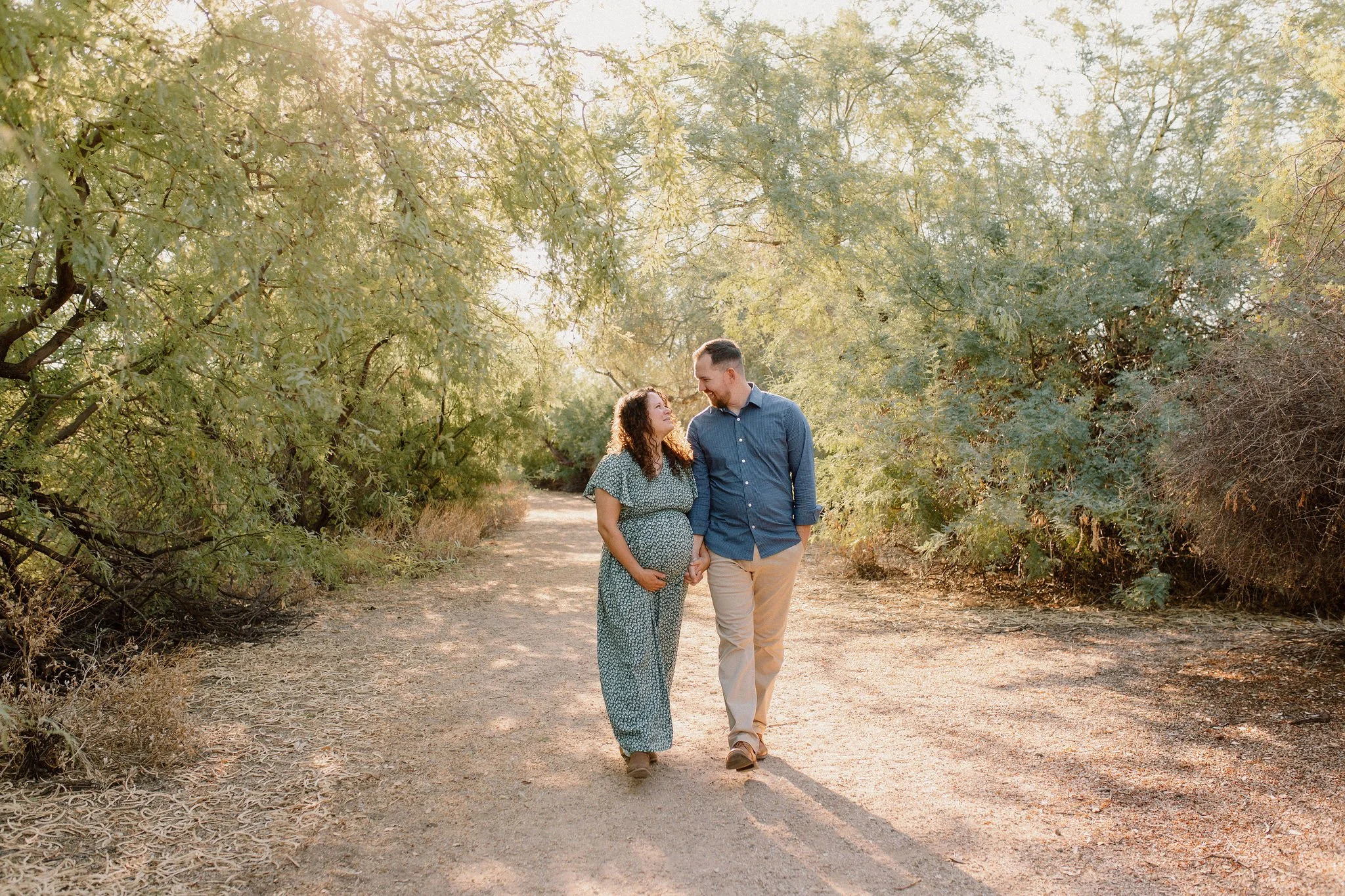 pregnant mom and dad walking and holding hands during family maternity photo session