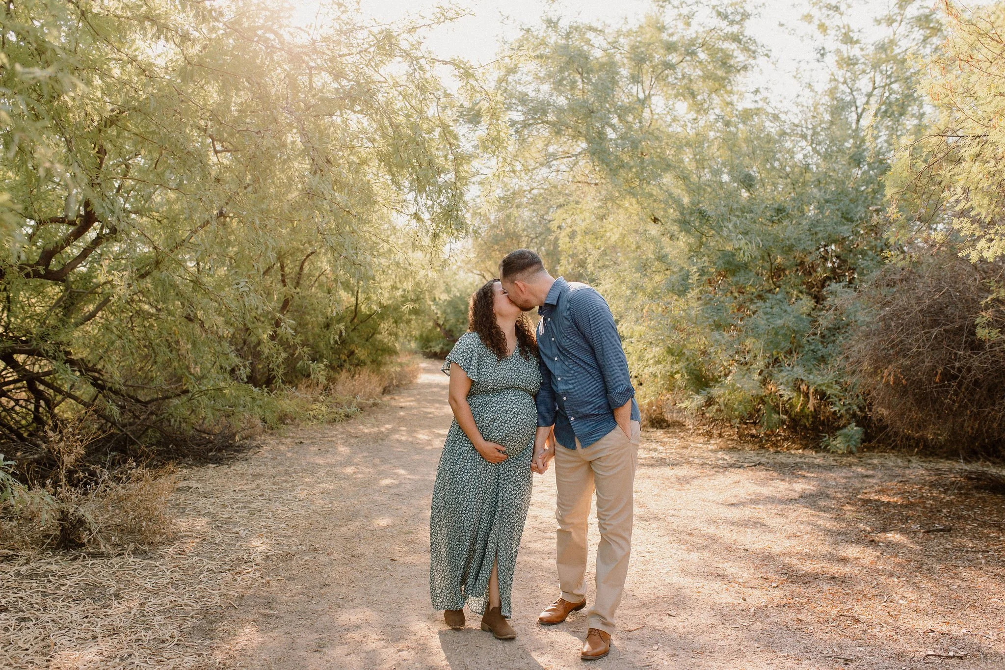 mom and dad walking and holding hands and kissing during family maternity photography session