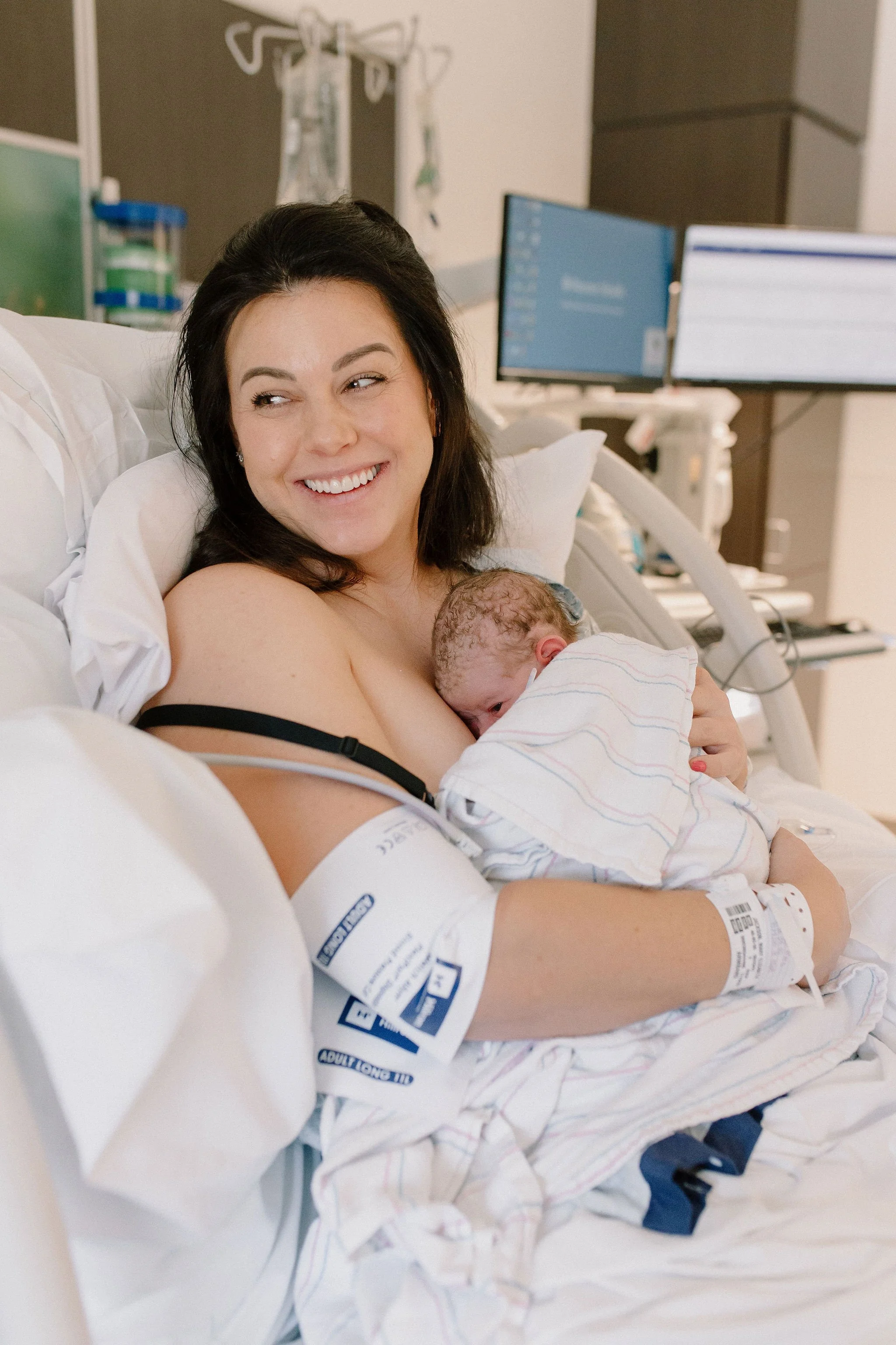 mom holding newborn baby after birth in hospital birth photography session