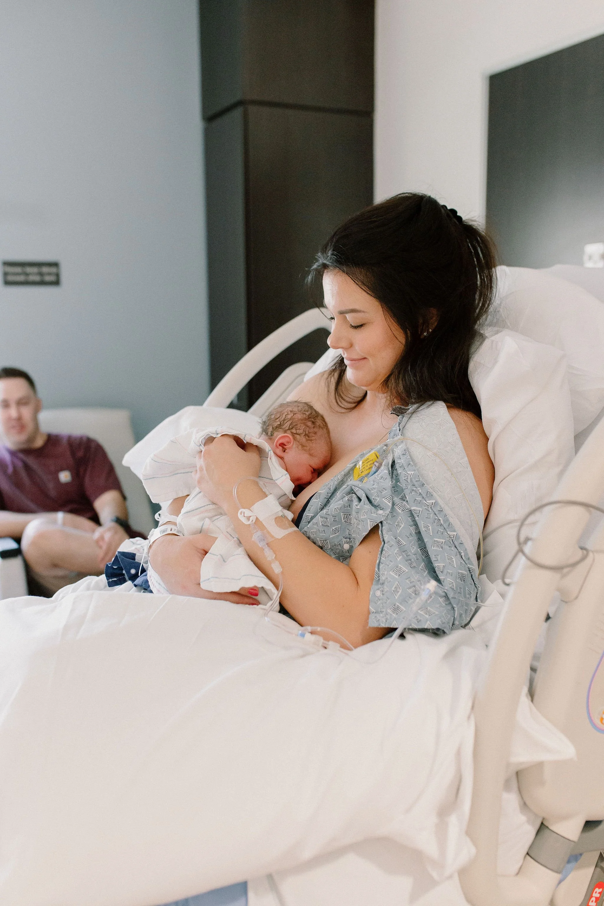 dad smiling at mom holding newborn baby girl after birth in hospital