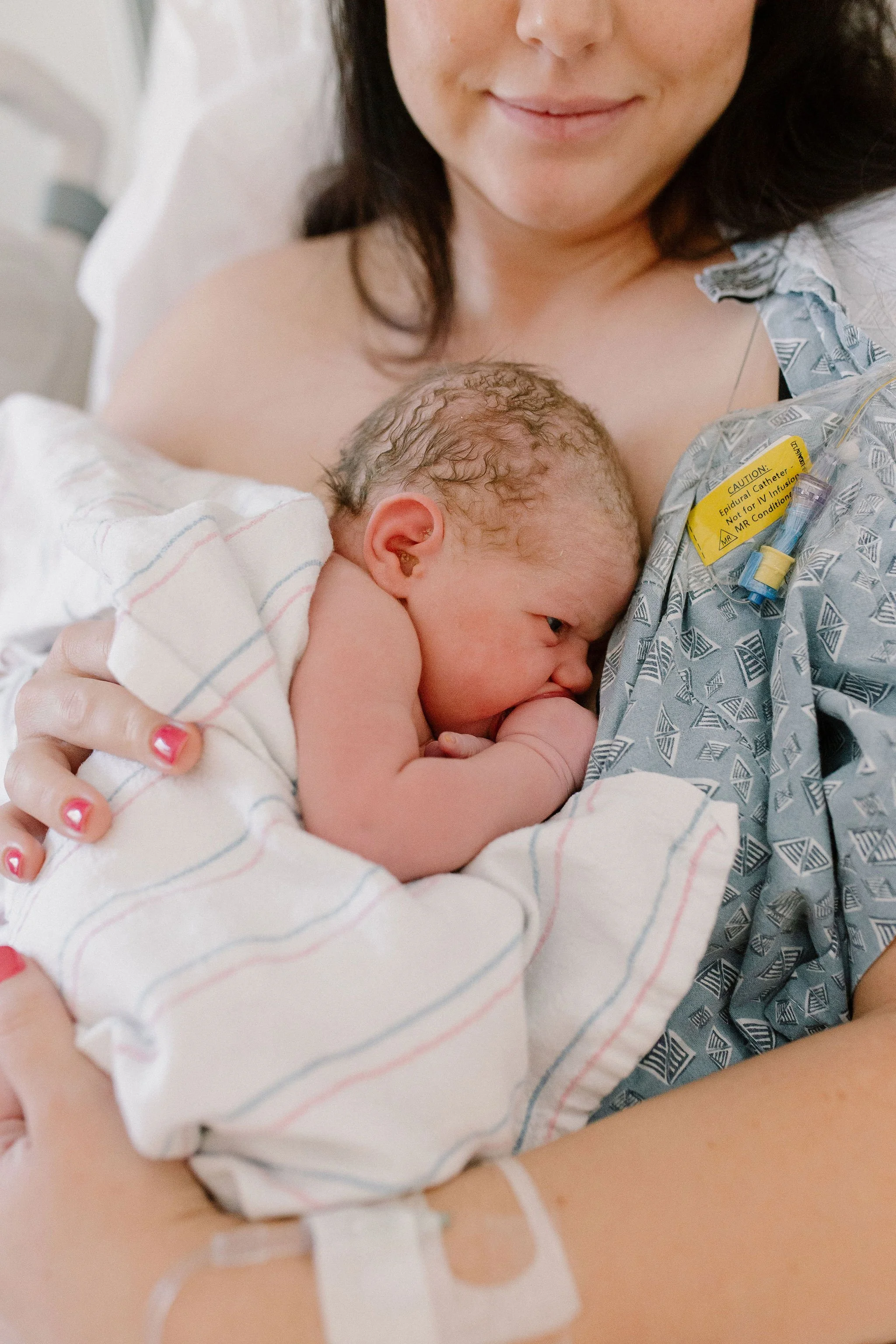 mom holding newborn baby girl in hospital bed after birth