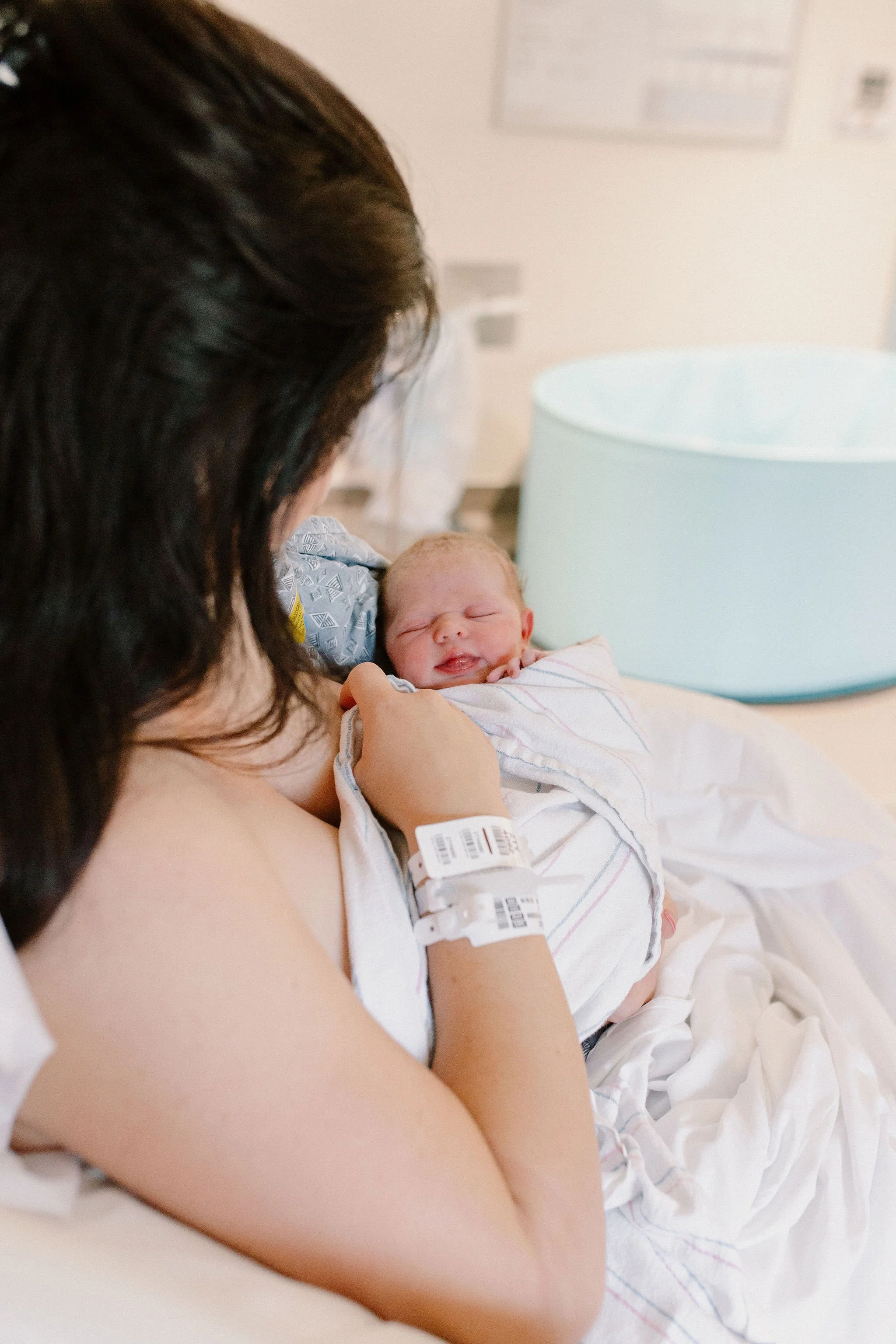mom holding newborn baby girl in hospital bed after birth