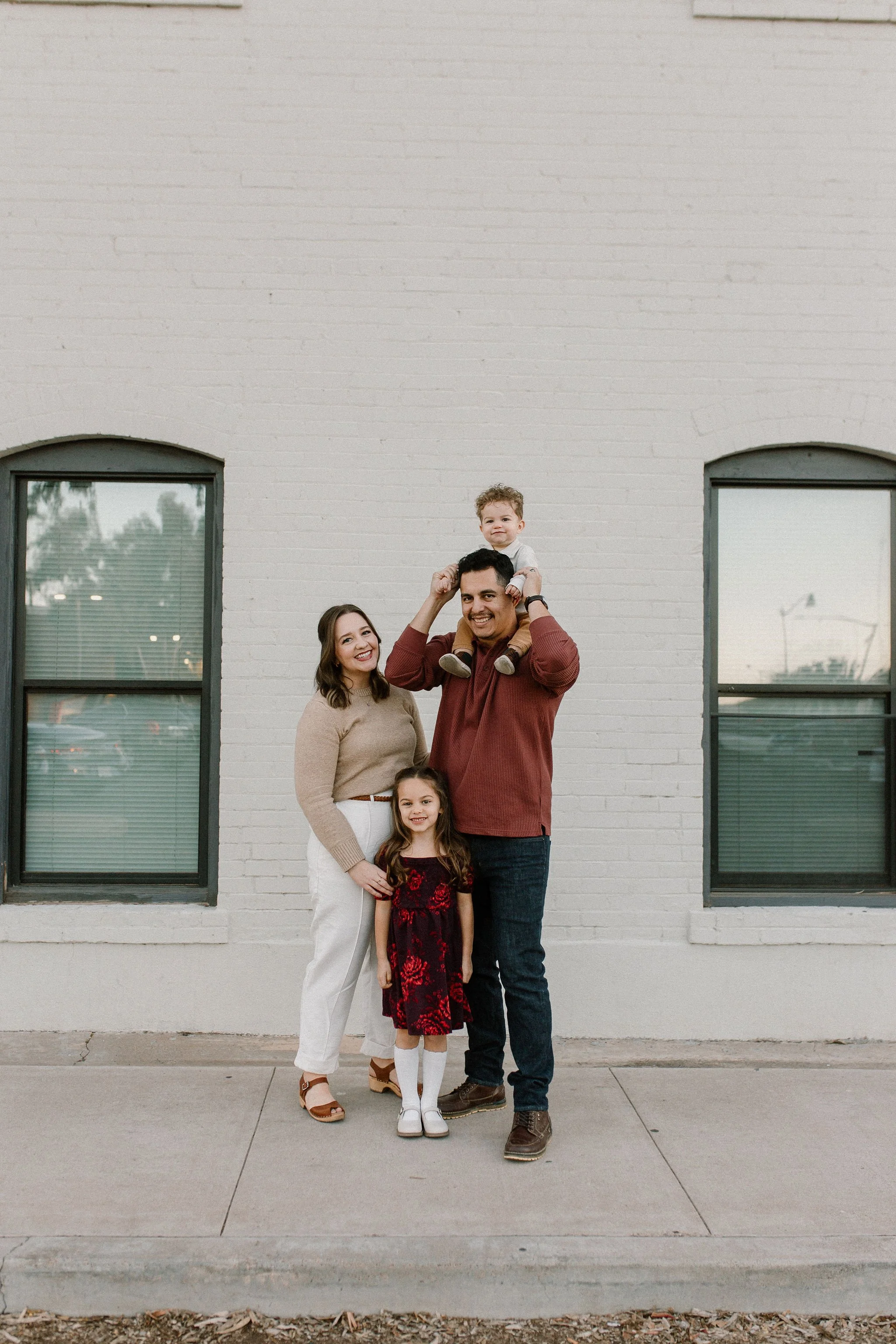 family of four standing together and smiling with son on dad's shoulders in downtown mesa family photography session