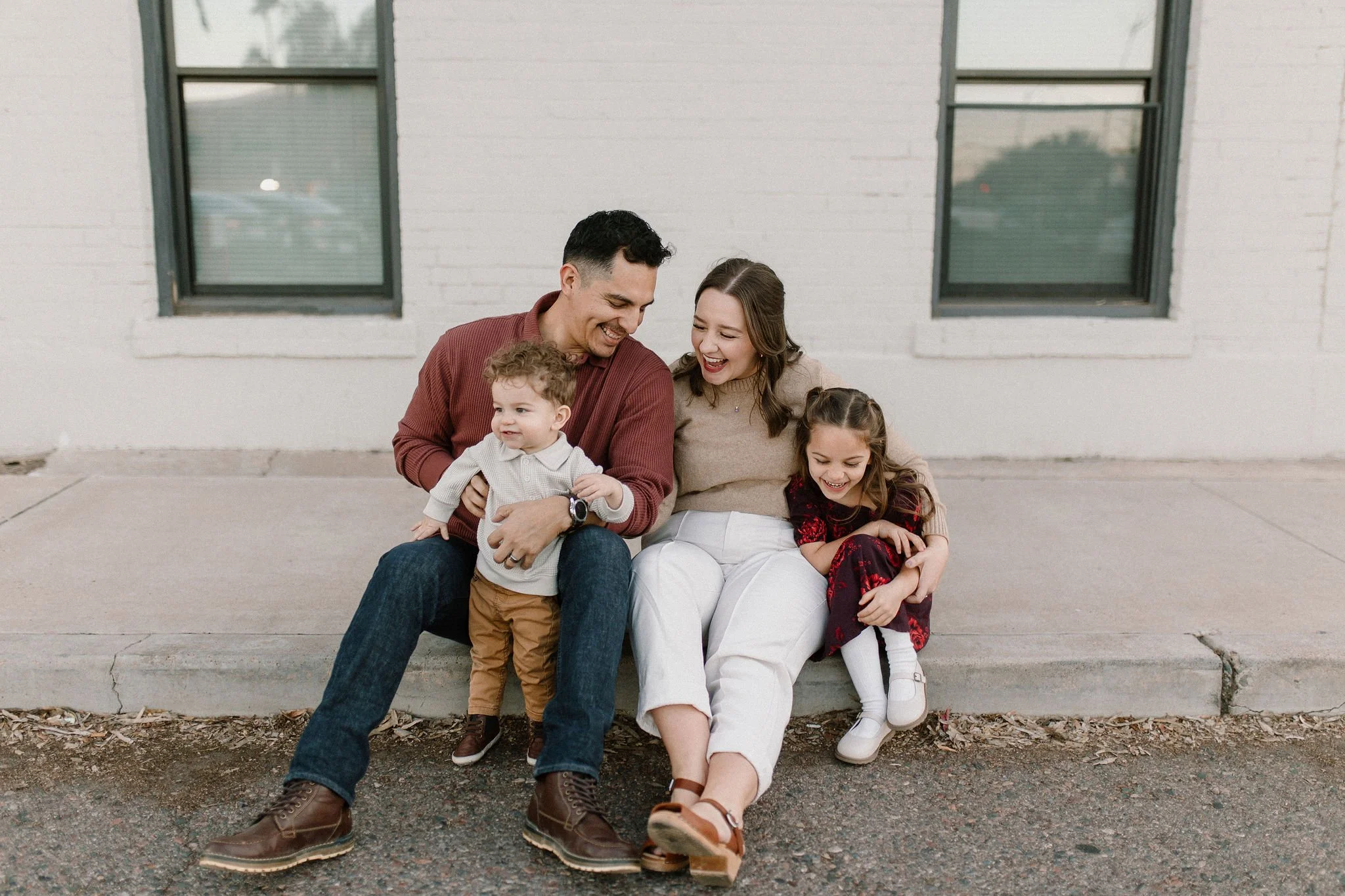 family of four sitting together smiling and laughing in fall downtown mesa family photography session