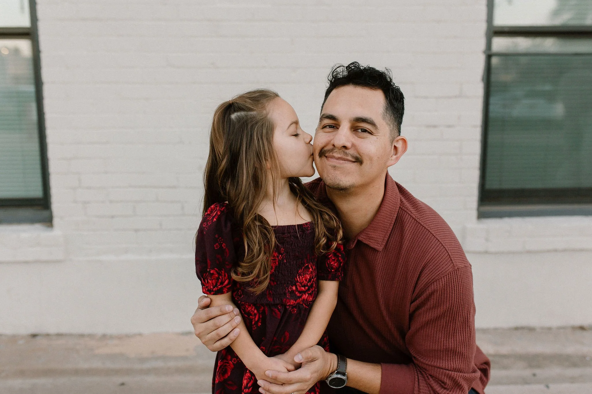 daughter kissing dad's cheek during downtown mesa family photos
