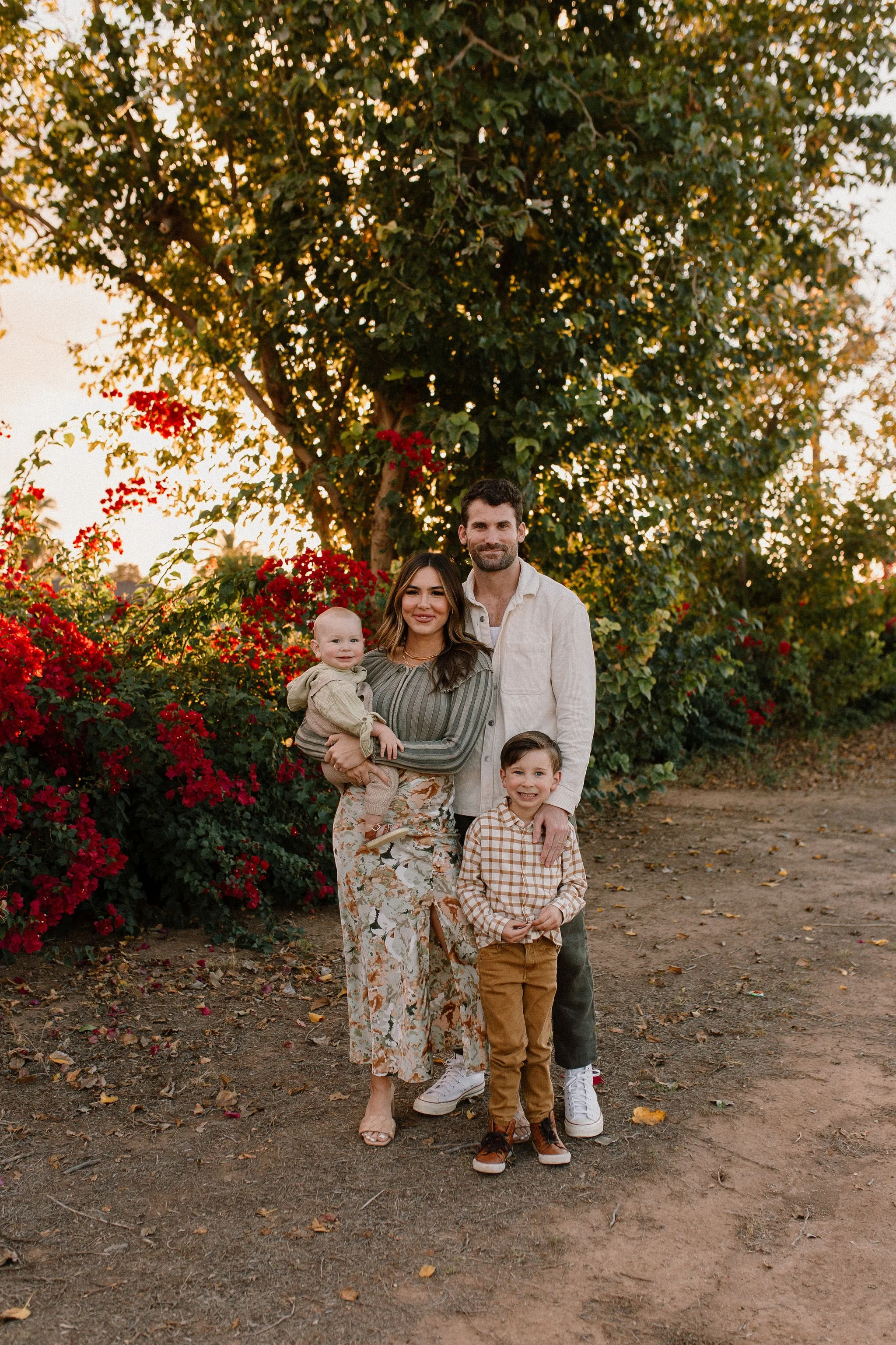 family of four standing together smiling in front of bougainvilleas during extend family photos