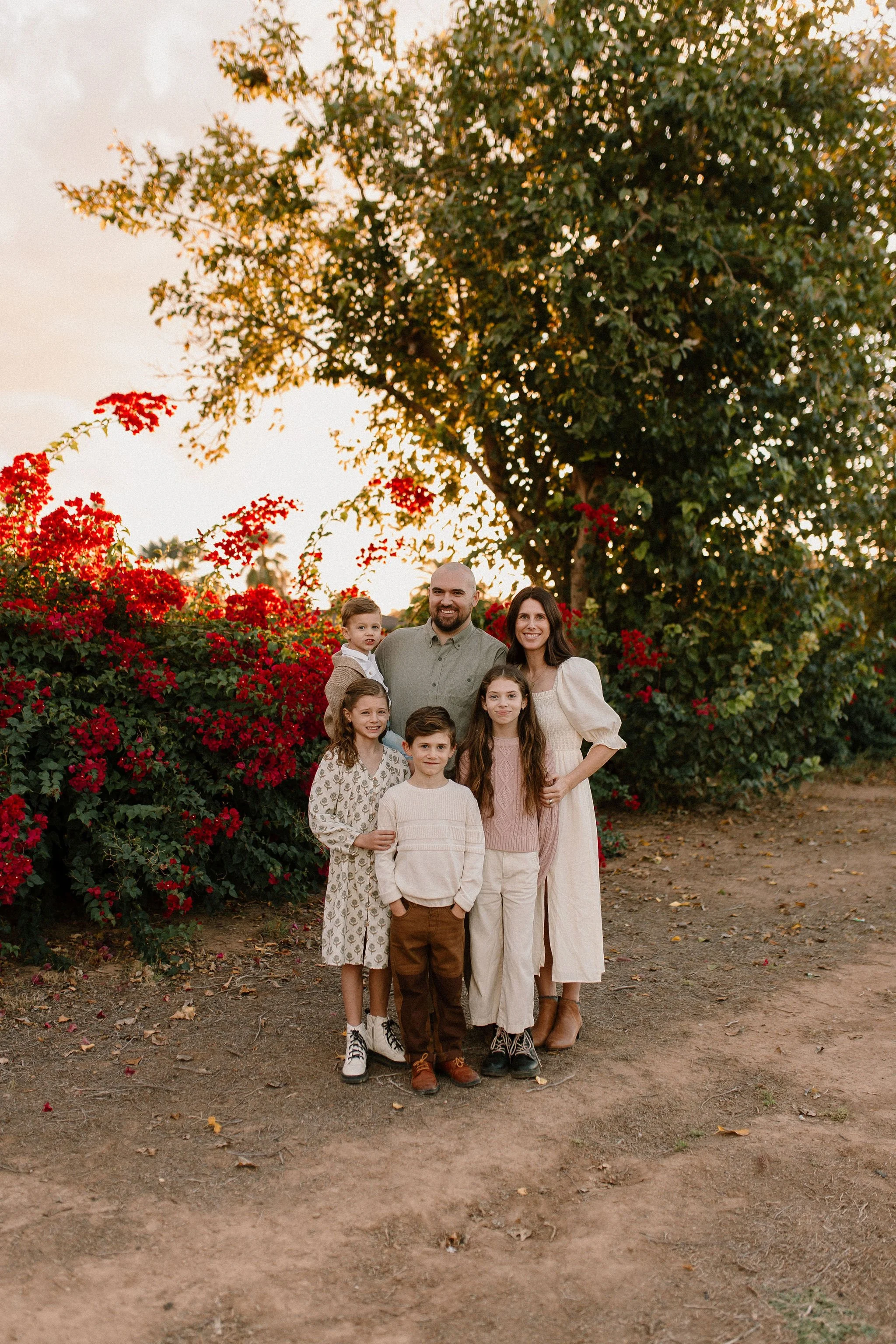 family of six standing together smiling in front of bougainvilleas during extended family photos session