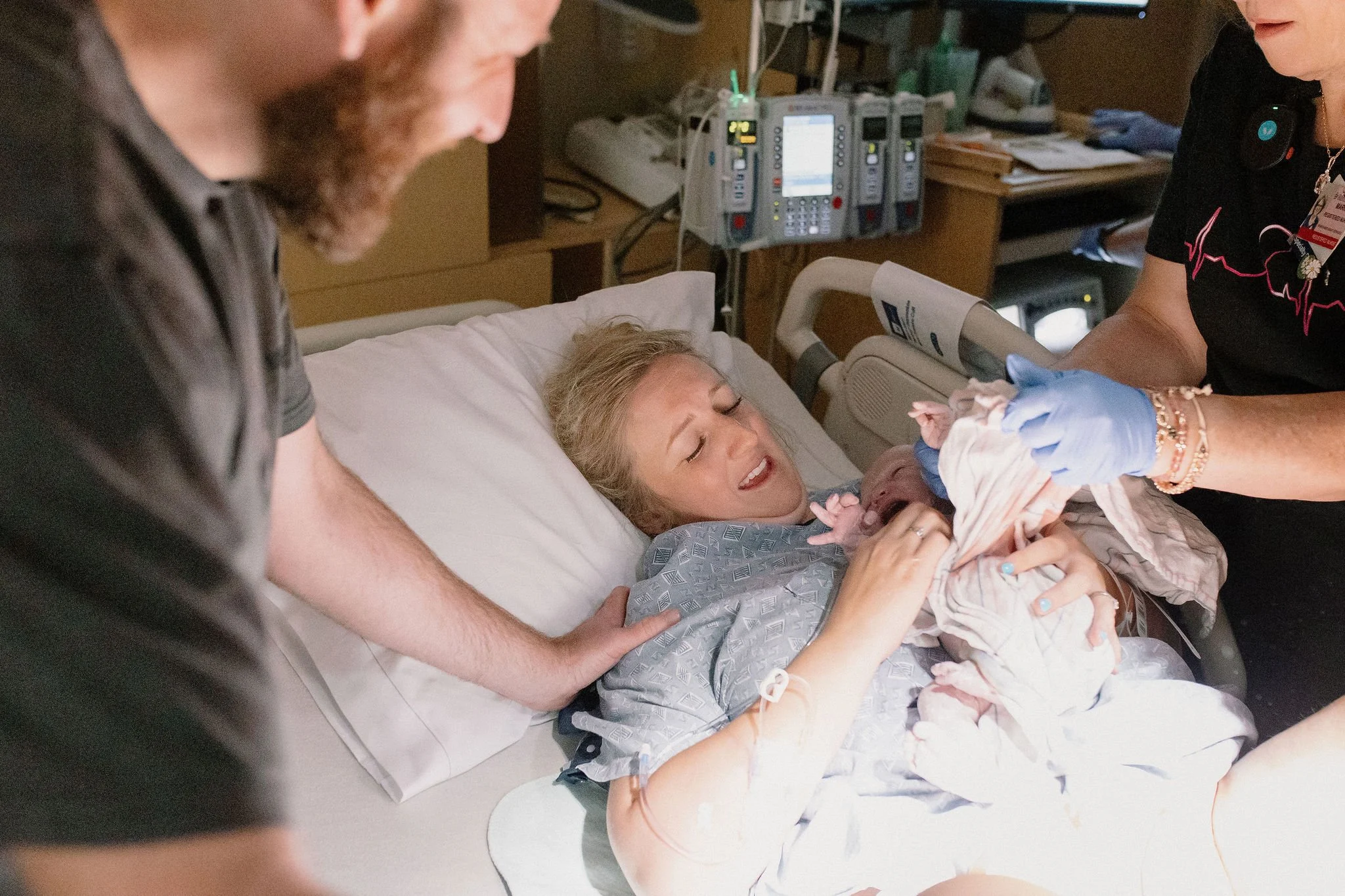 mom holding newborn baby immediately after birth with dad supporting mom during hospital birth